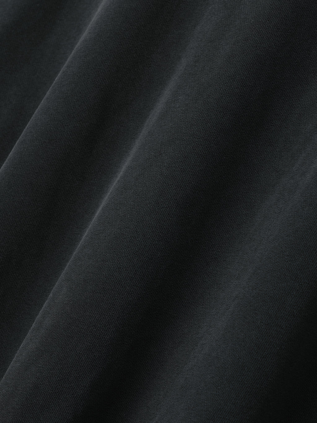 Close-up view of smooth black fabric with soft folds and fine knit texture visible under lighting