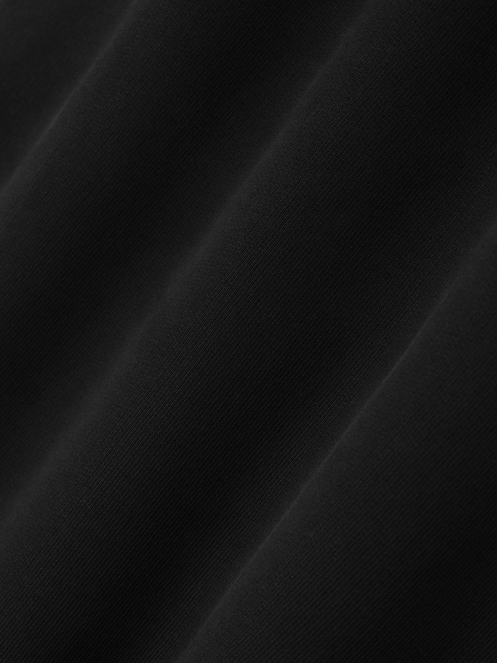 close-up of smooth black cotton fleece fabric texture with soft drape and subtle diagonal folds