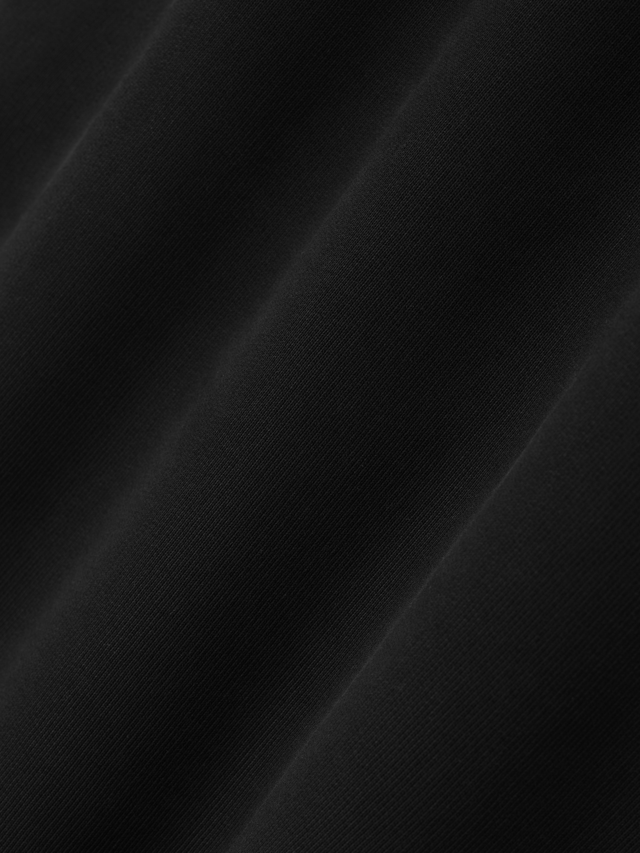 close-up of smooth black cotton fleece fabric texture with soft drape and subtle diagonal folds