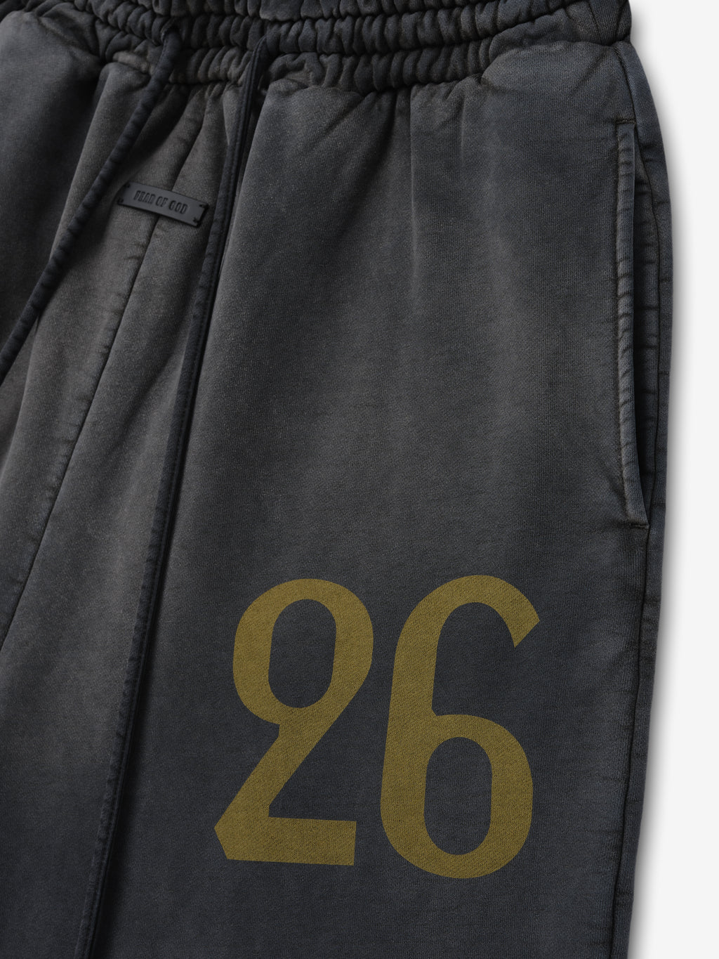 Off-black sweatpants with elastic waistband and large muted gold number "26" printed on the upper thigh area