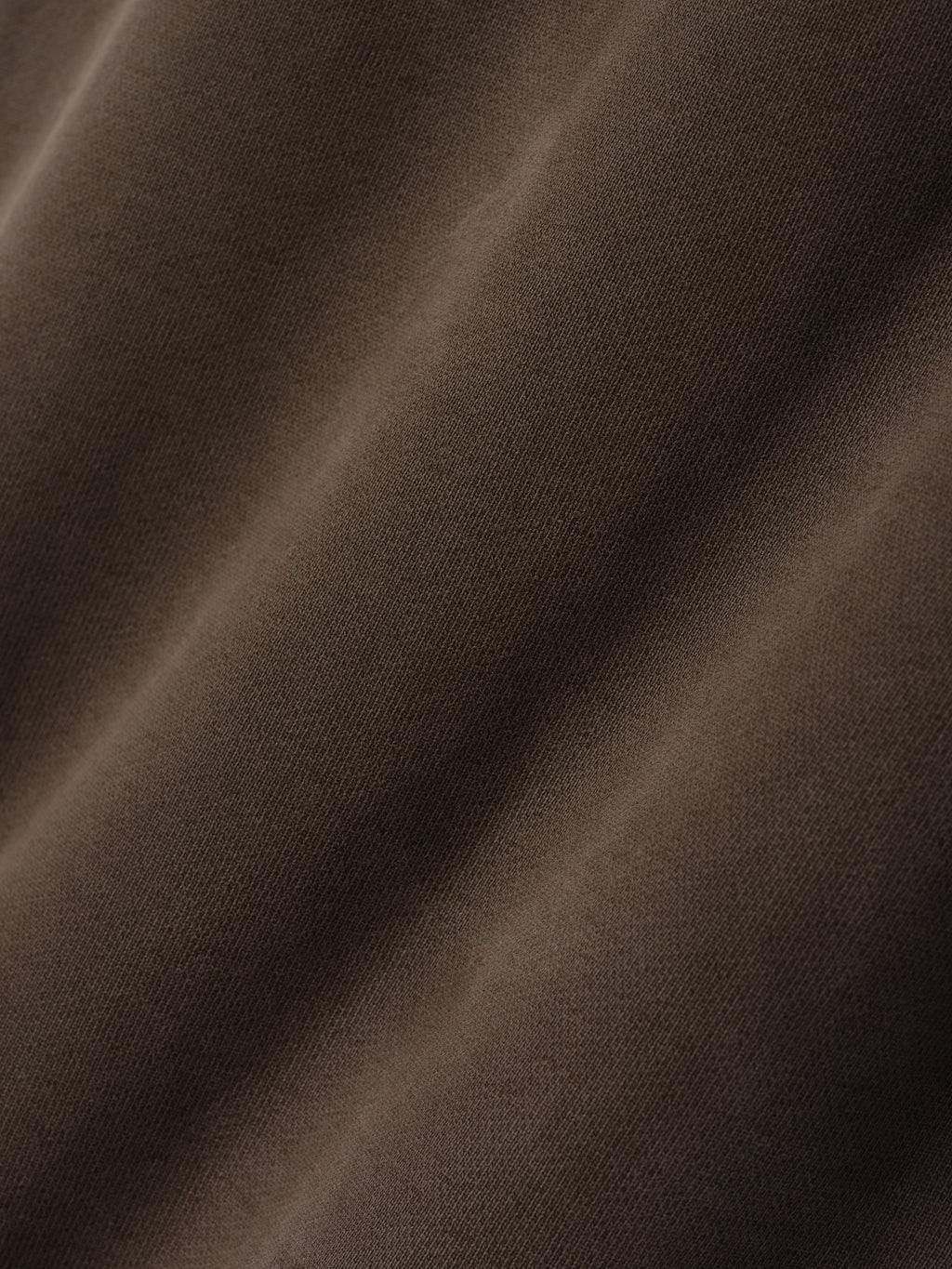 Close-up of smooth faded brown fabric with subtle texture and soft light highlighting fine knit details