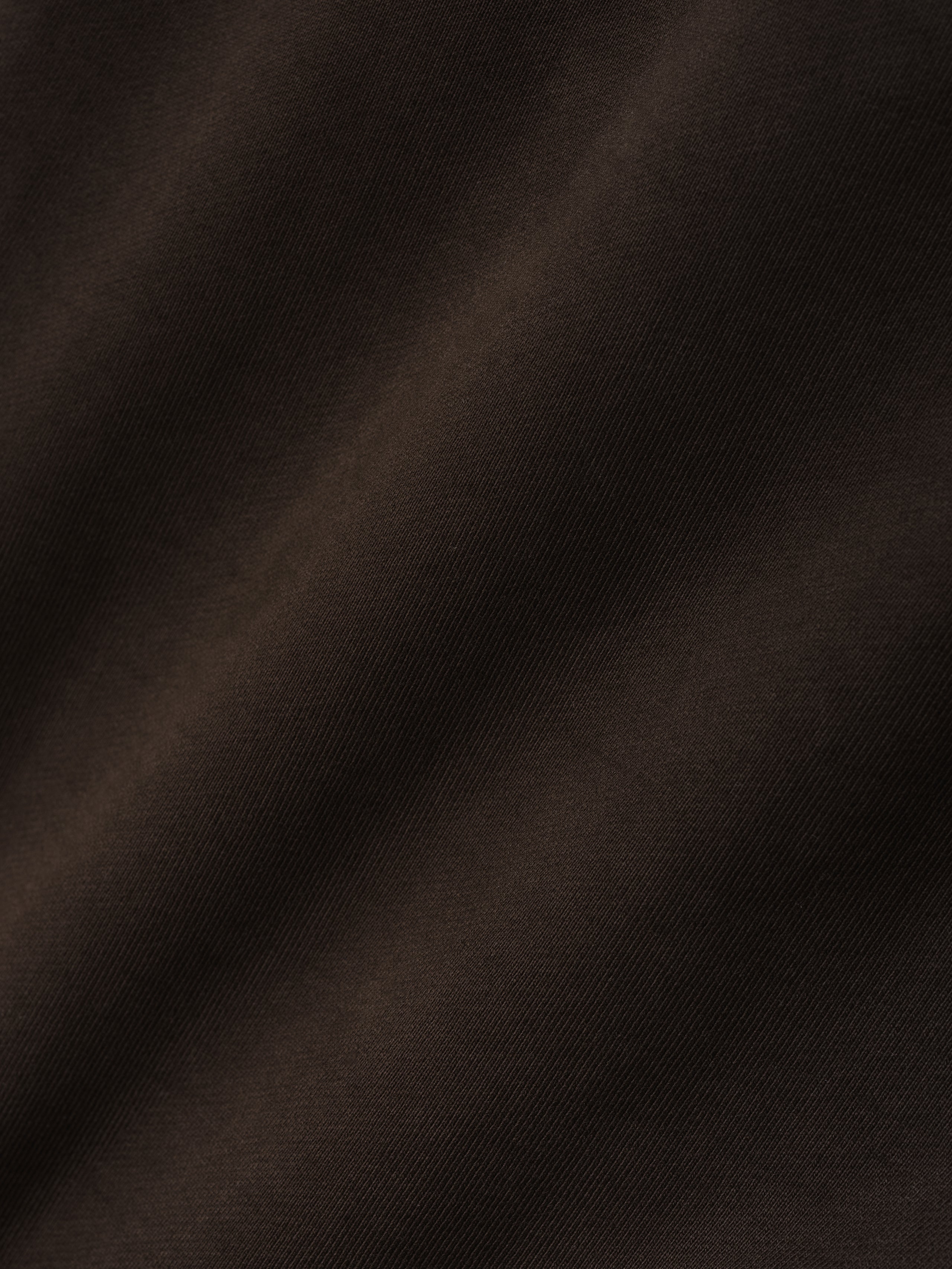 Close-up of dark brown fabric with a soft, smooth texture and subtle diagonal weave pattern