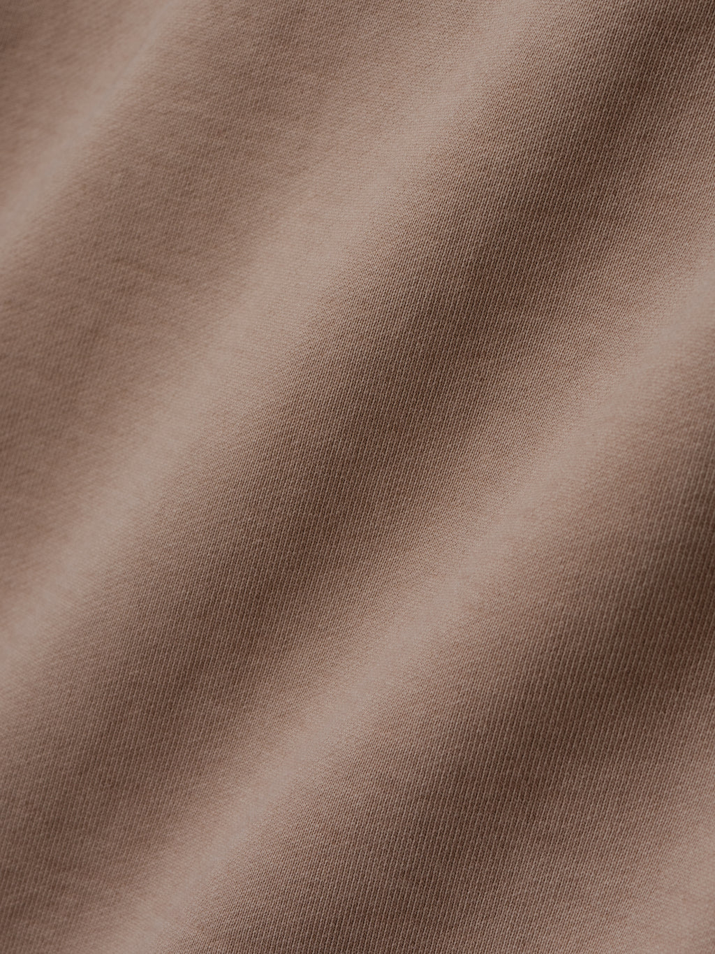 close-up of taupe heavyweight cotton fleece fabric with soft texture and sunfade garment wash finish