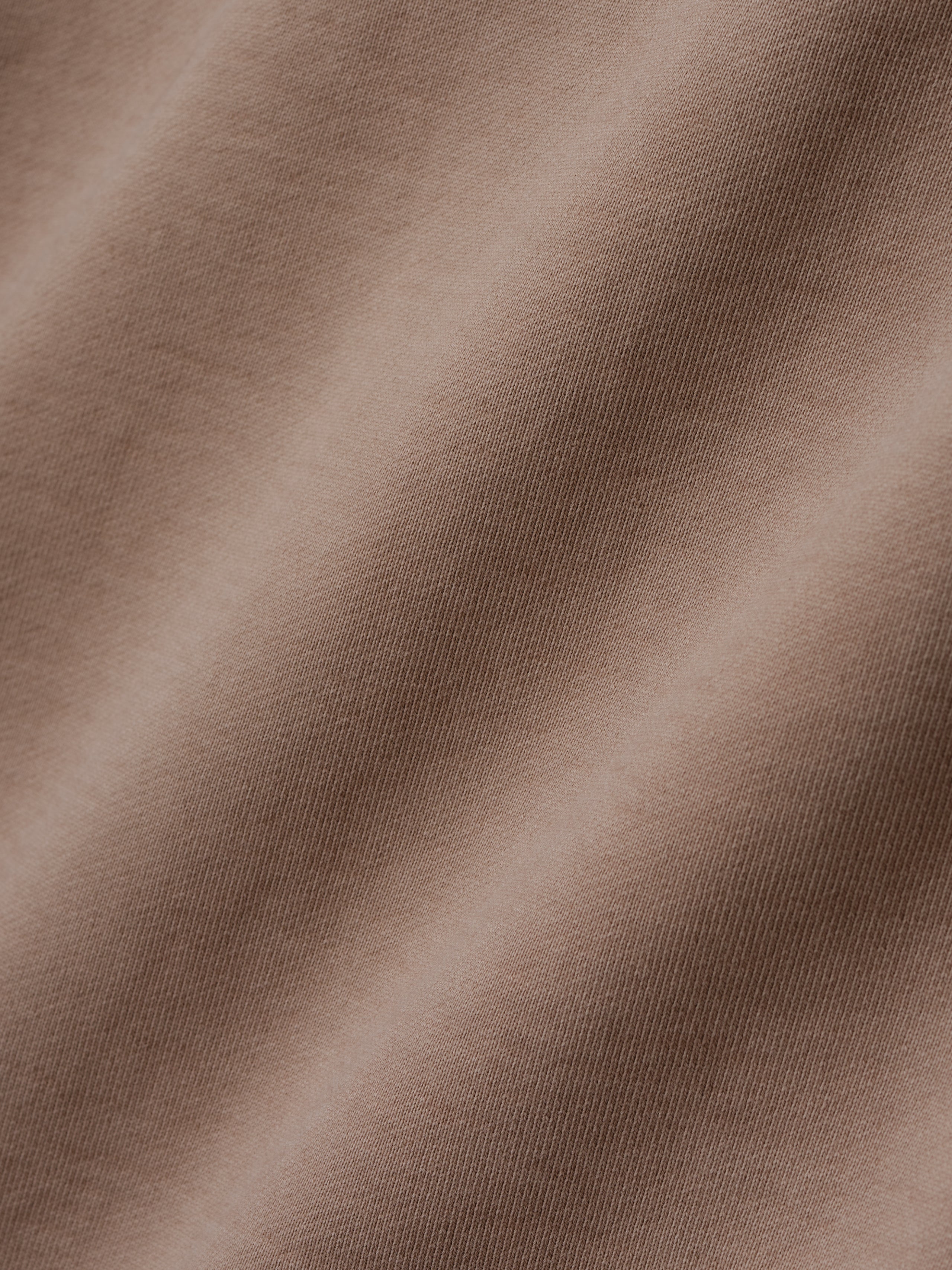 close-up of taupe heavyweight cotton fleece fabric with soft texture and sunfade garment wash finish