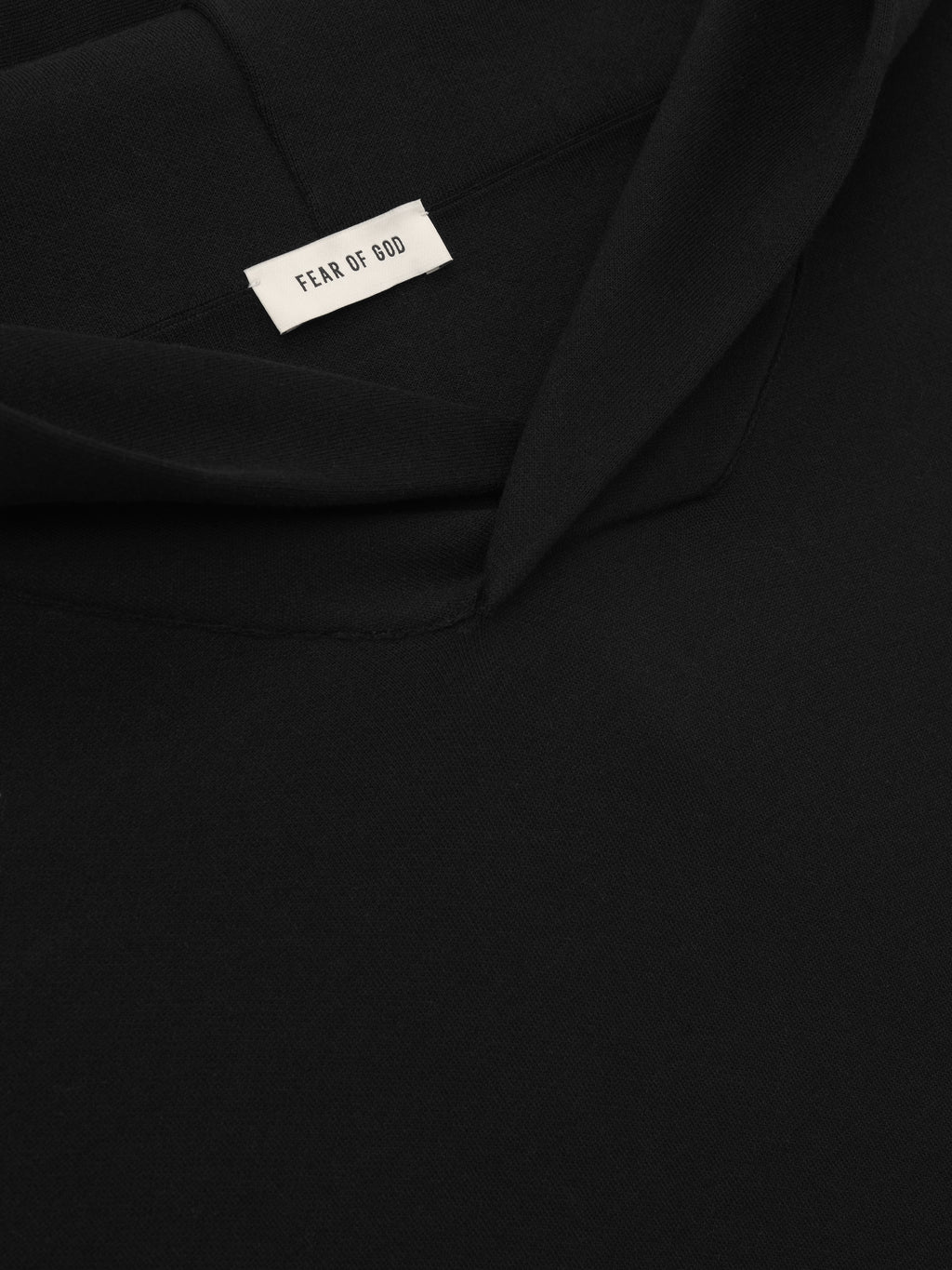 close-up of black double knit hoodie with Fear of God label and structured hood in compact cotton-nylon fabric