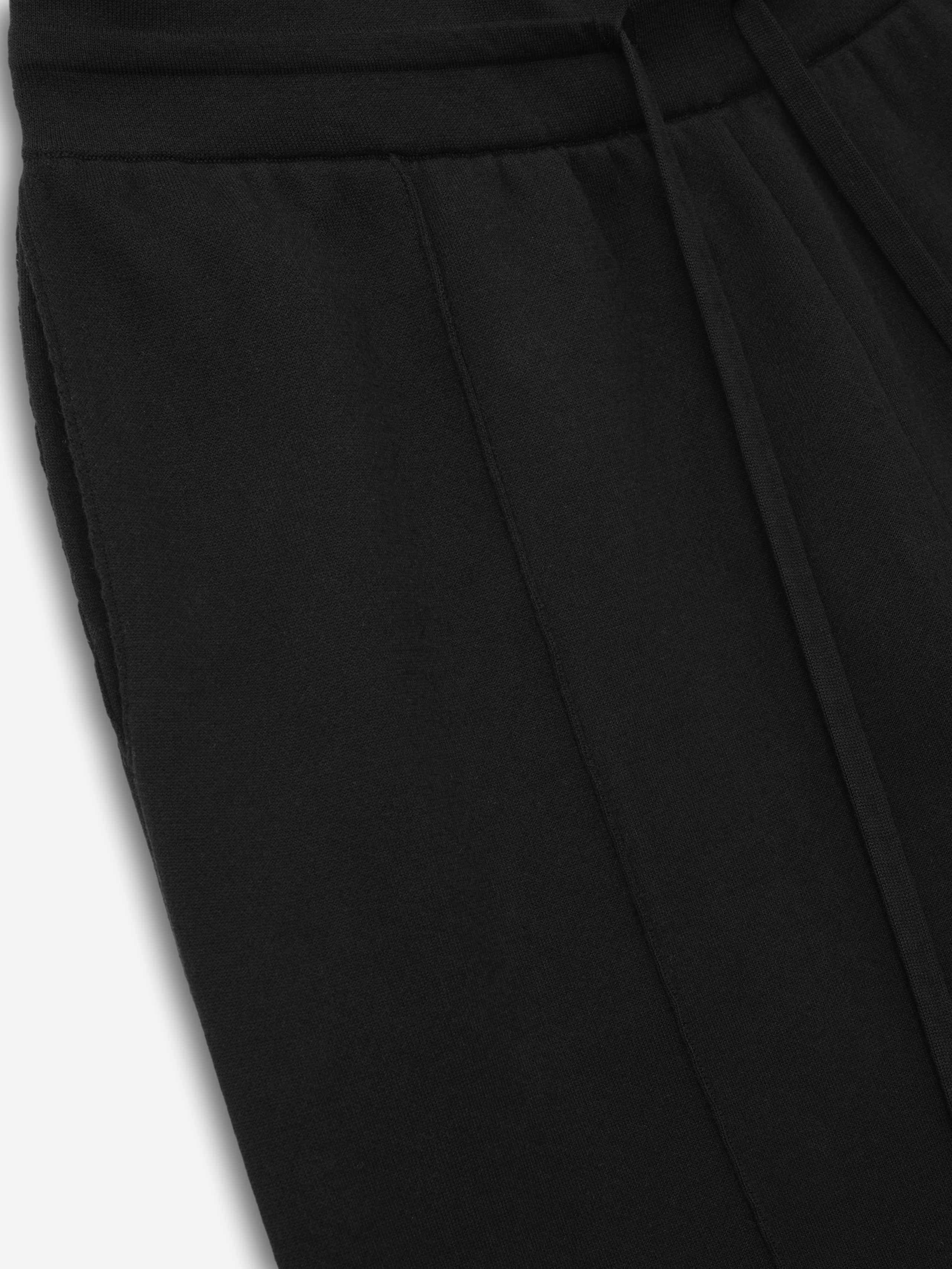 close-up of black cotton-nylon double-knit fabric showing elastic waistband and front seam detail of jogging pants