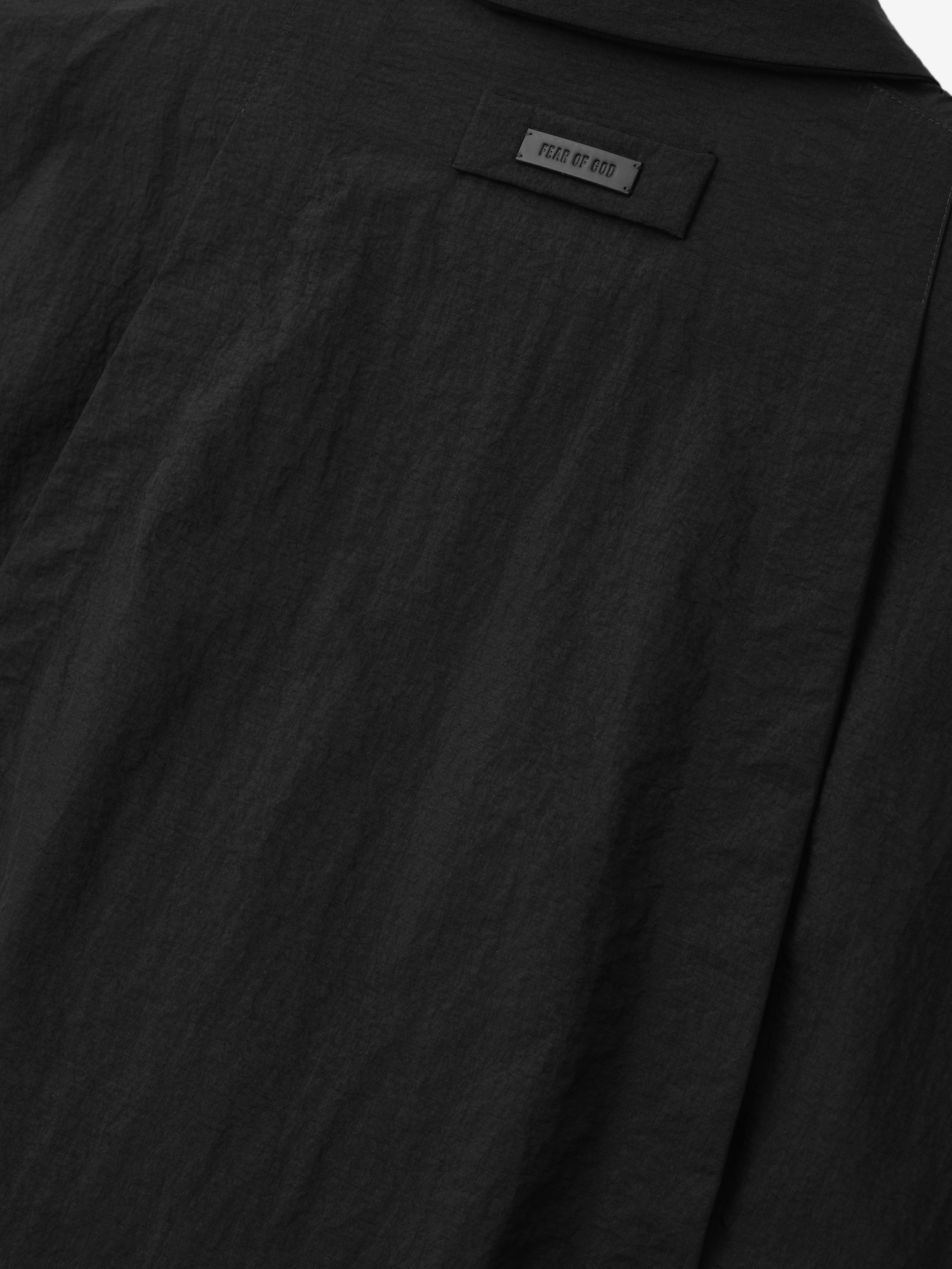 close-up of black recycled nylon ripstop fabric with subtle texture and Fear of God logo patch on back panel