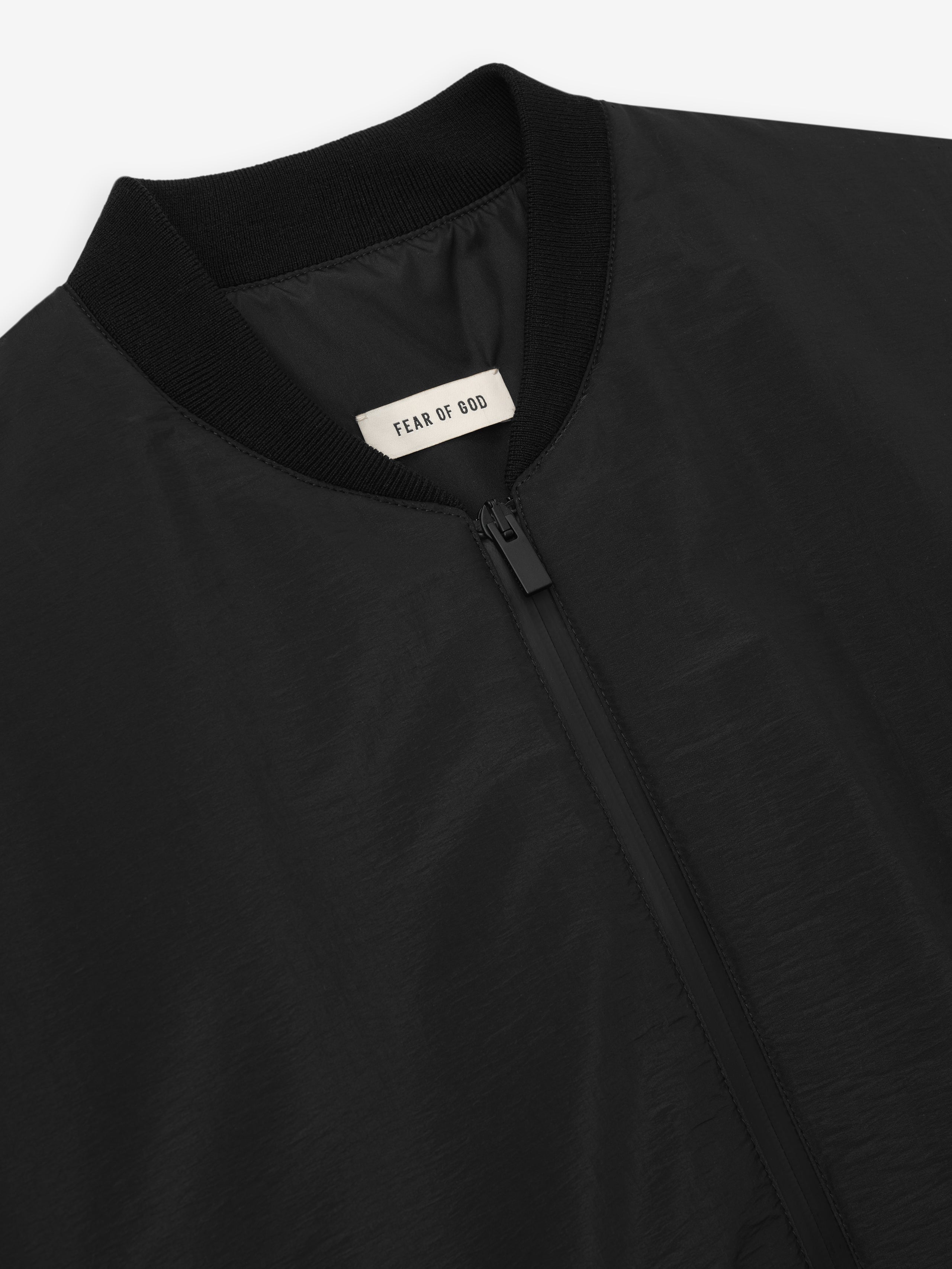 close-up of black nylon taffeta padded bomber jacket with knit collar and front zipper detail