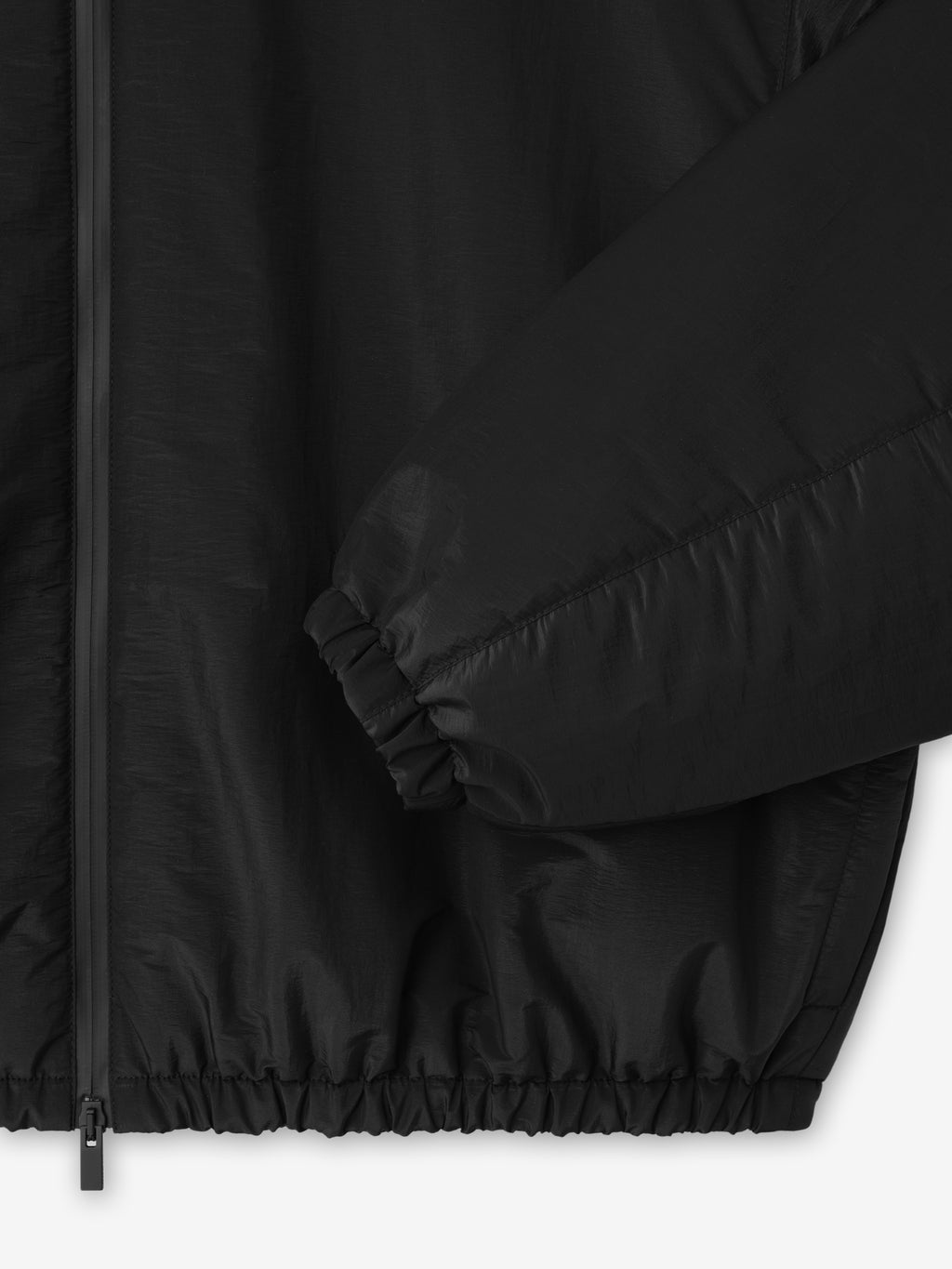 close-up detail of black nylon taffeta padded bomber jacket sleeve with elasticated cuff and front zipper panel