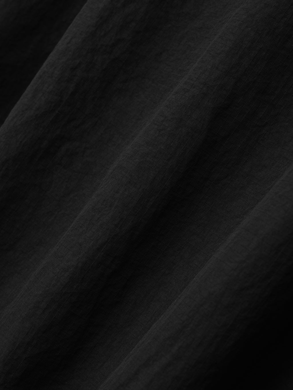 close-up texture of black lightweight recycled nylon ripstop fabric used in Tech Track Jacket