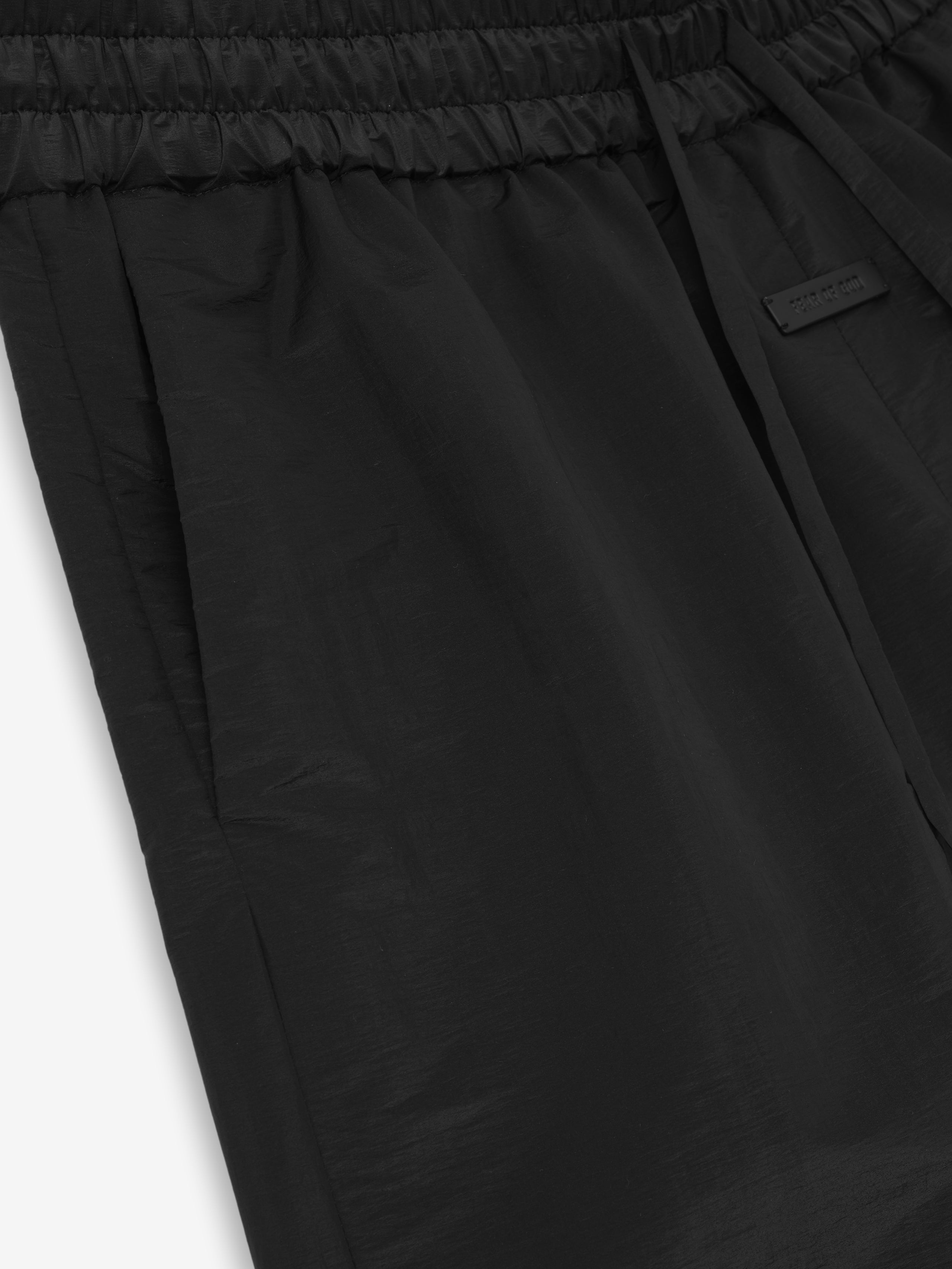 close-up of black lightweight nylon taffeta padded sport shorts with elasticated waistband and discreet side pocket detail