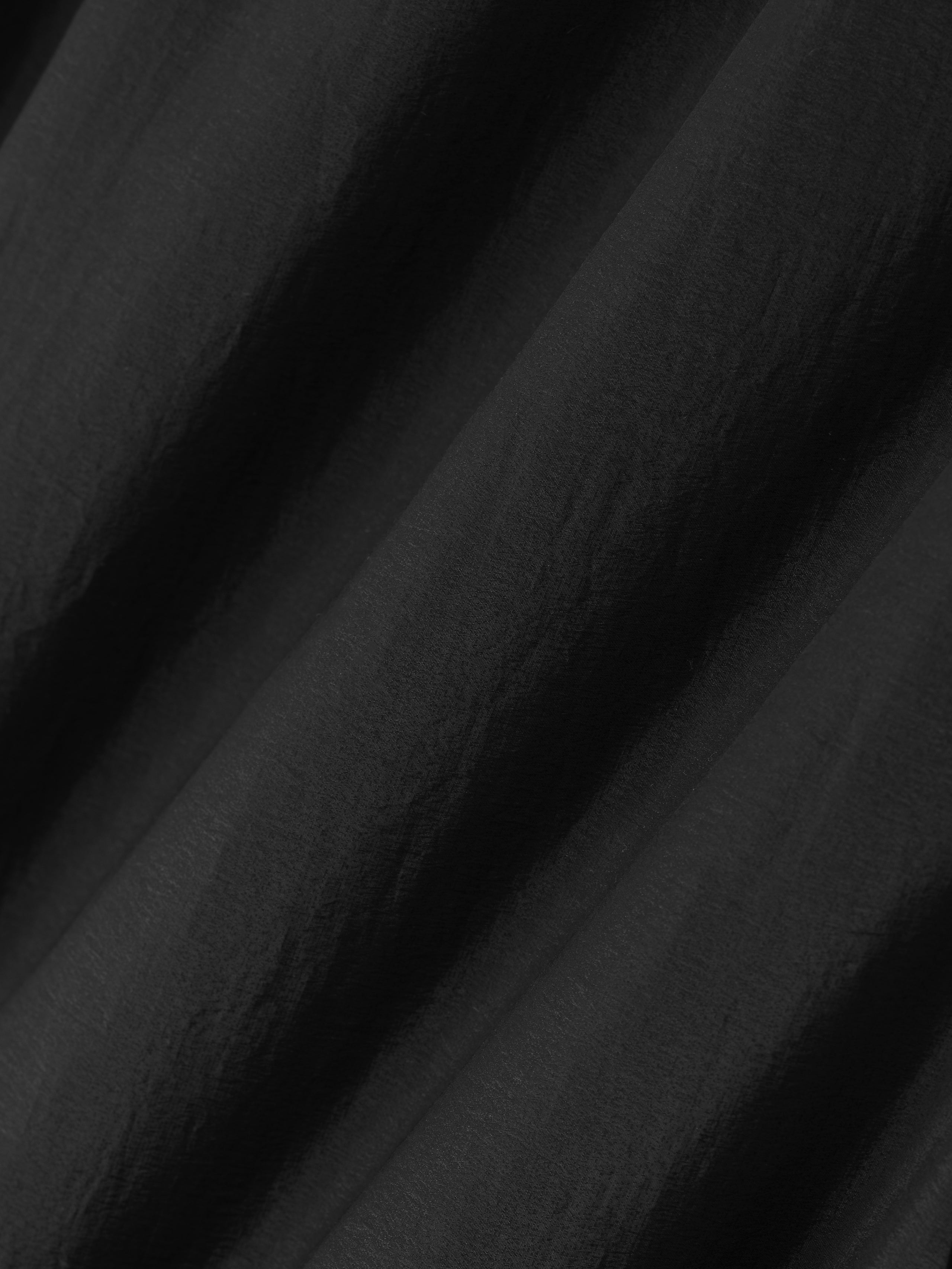 close-up of crinkled black nylon taffeta fabric with a subtle sheen used in padded sport shorts