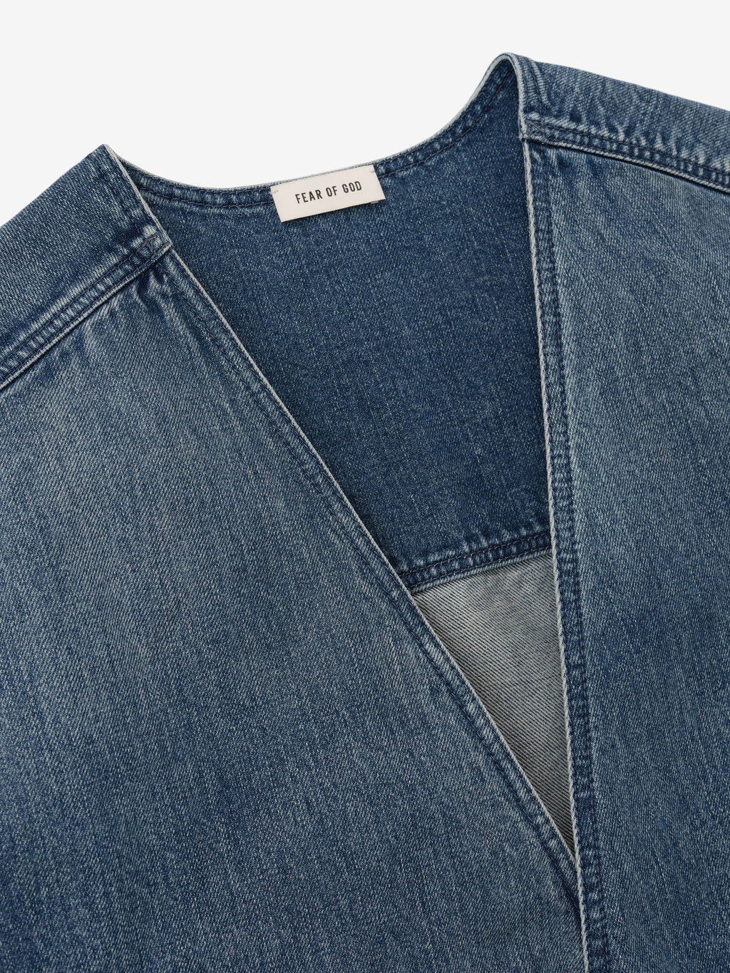 close-up of men's denim lapelless jacket neckline with visible Fear of God label and classic blue indigo wash fabric
