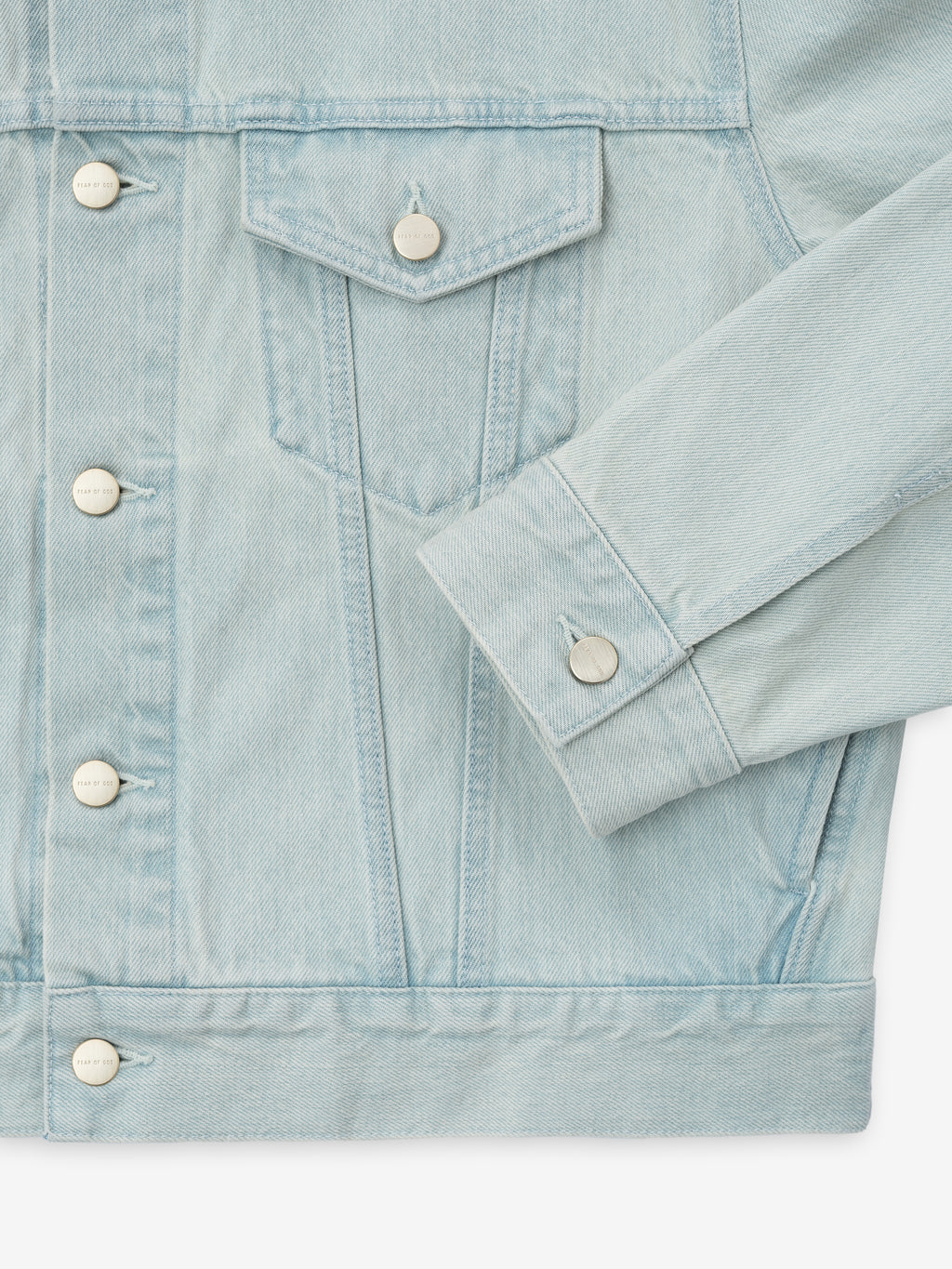 close-up of men's bleached denim trucker jacket front with flap chest pocket and Fear of God metal buttons