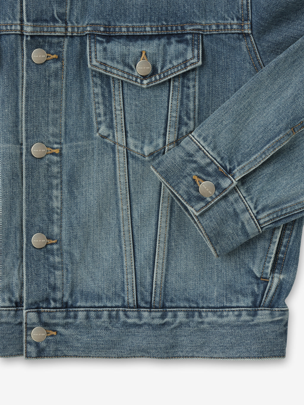 close-up of medium indigo denim trucker jacket showing chest flap pocket, metal buttons, and cuff detail