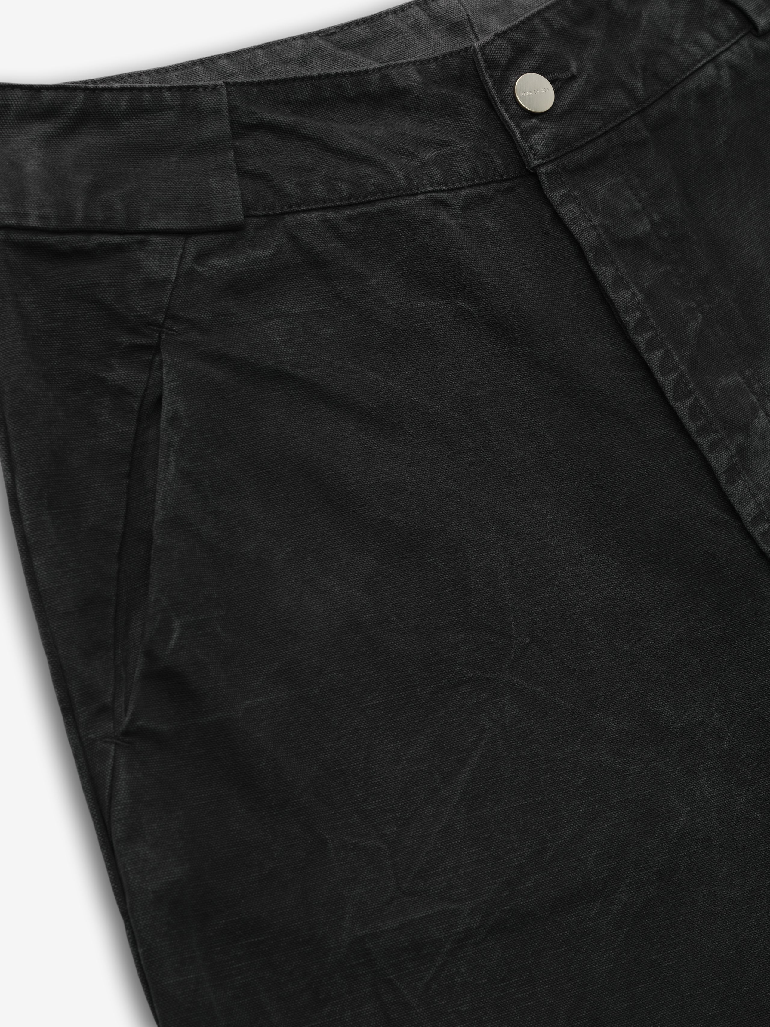close-up of black washed canvas utility pant front with metal button closure and front seam pocket detailing