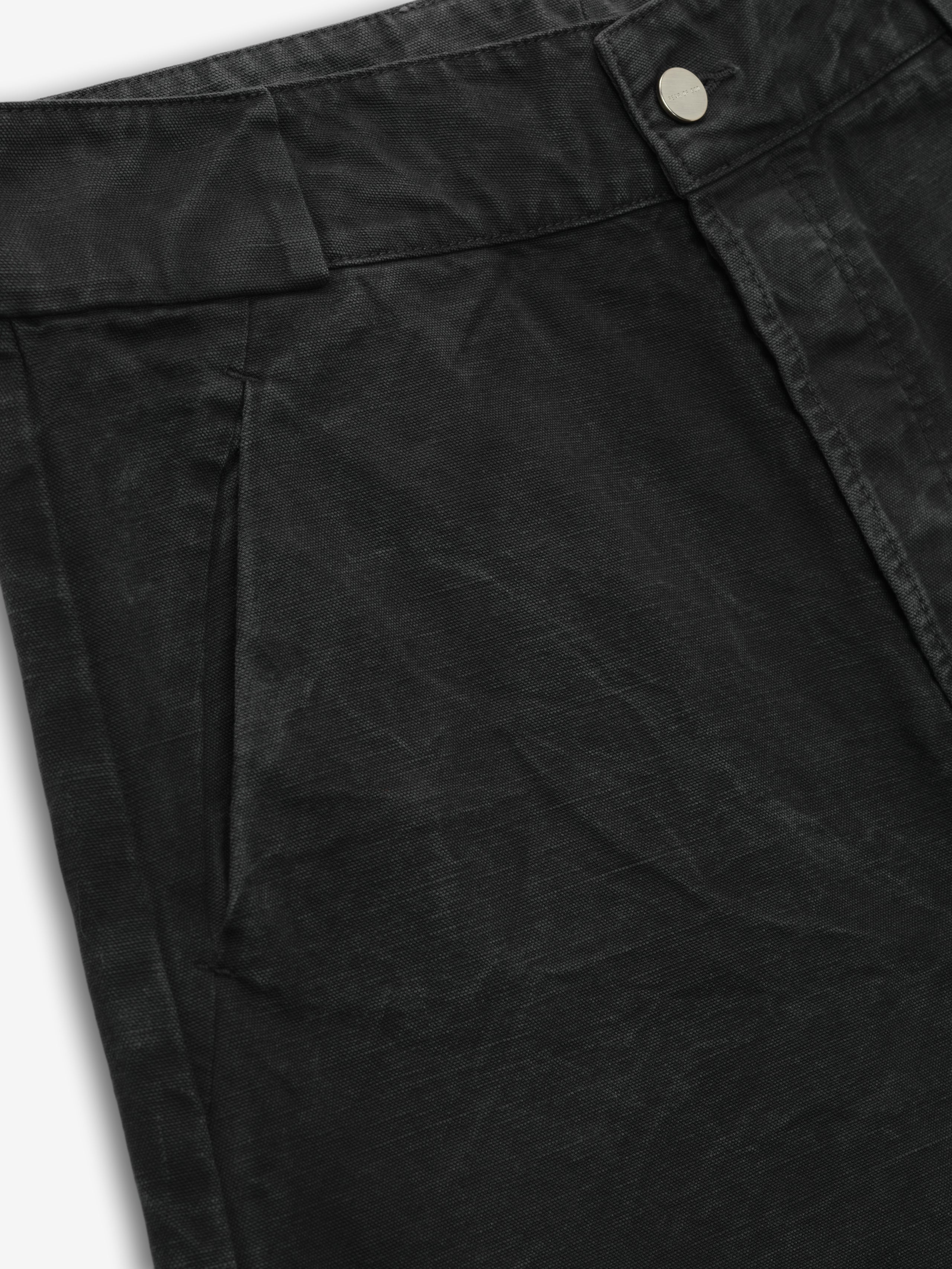 close-up detail of front pocket and waistband button on black washed cotton canvas utility shorts