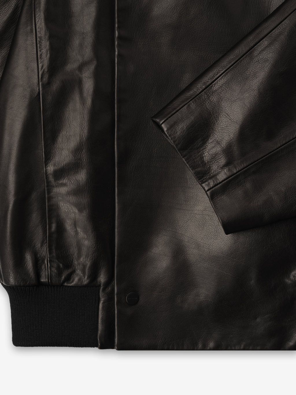 close-up of black full grain calfskin raglan bomber jacket with snap button closure and ribbed knit hem and sleeve cuff