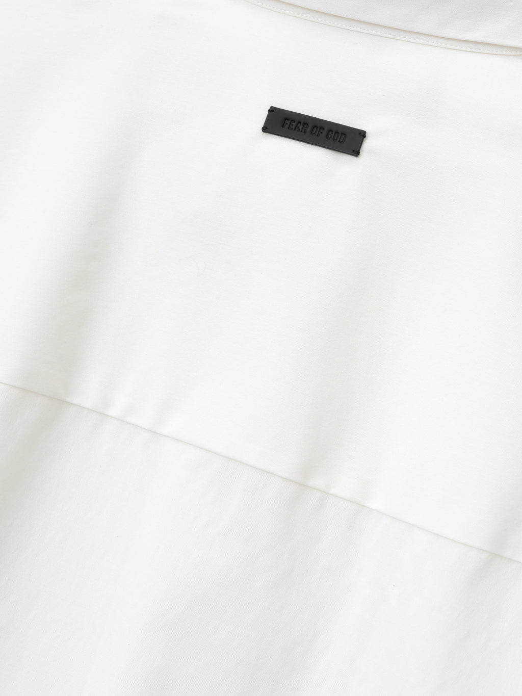 close-up detail of white cotton wool oxford shirt showing black Fear of God label stitched above horizontal seam