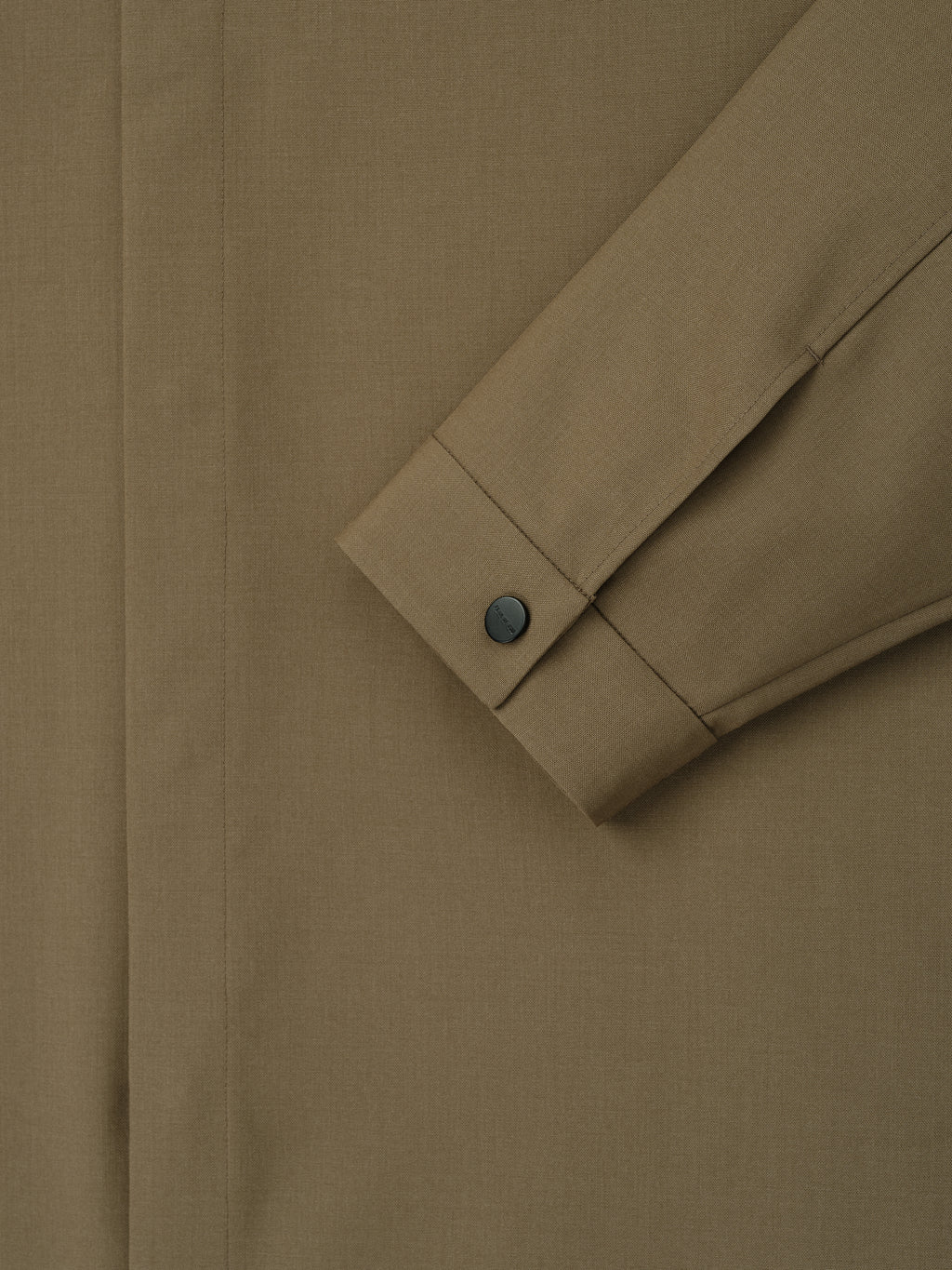 Close-up of clay-colored shirt sleeve with buttoned cuff and concealed placket on smooth woven fabric