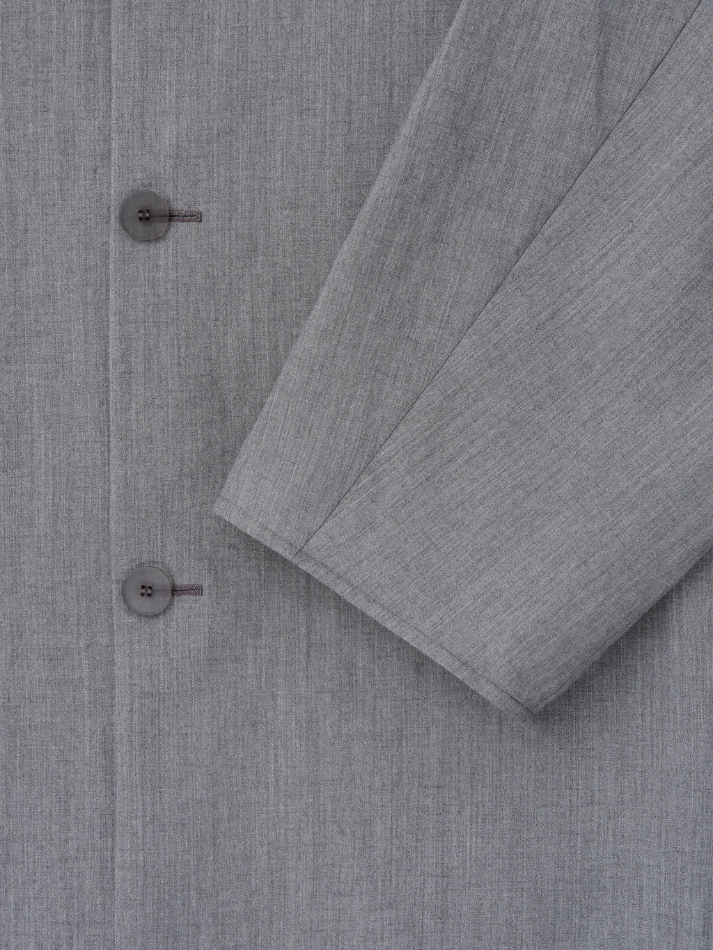 close-up of light grey washed wool-linen fabric with subtle texture and two-button detail on collarless sport jacket sleeve