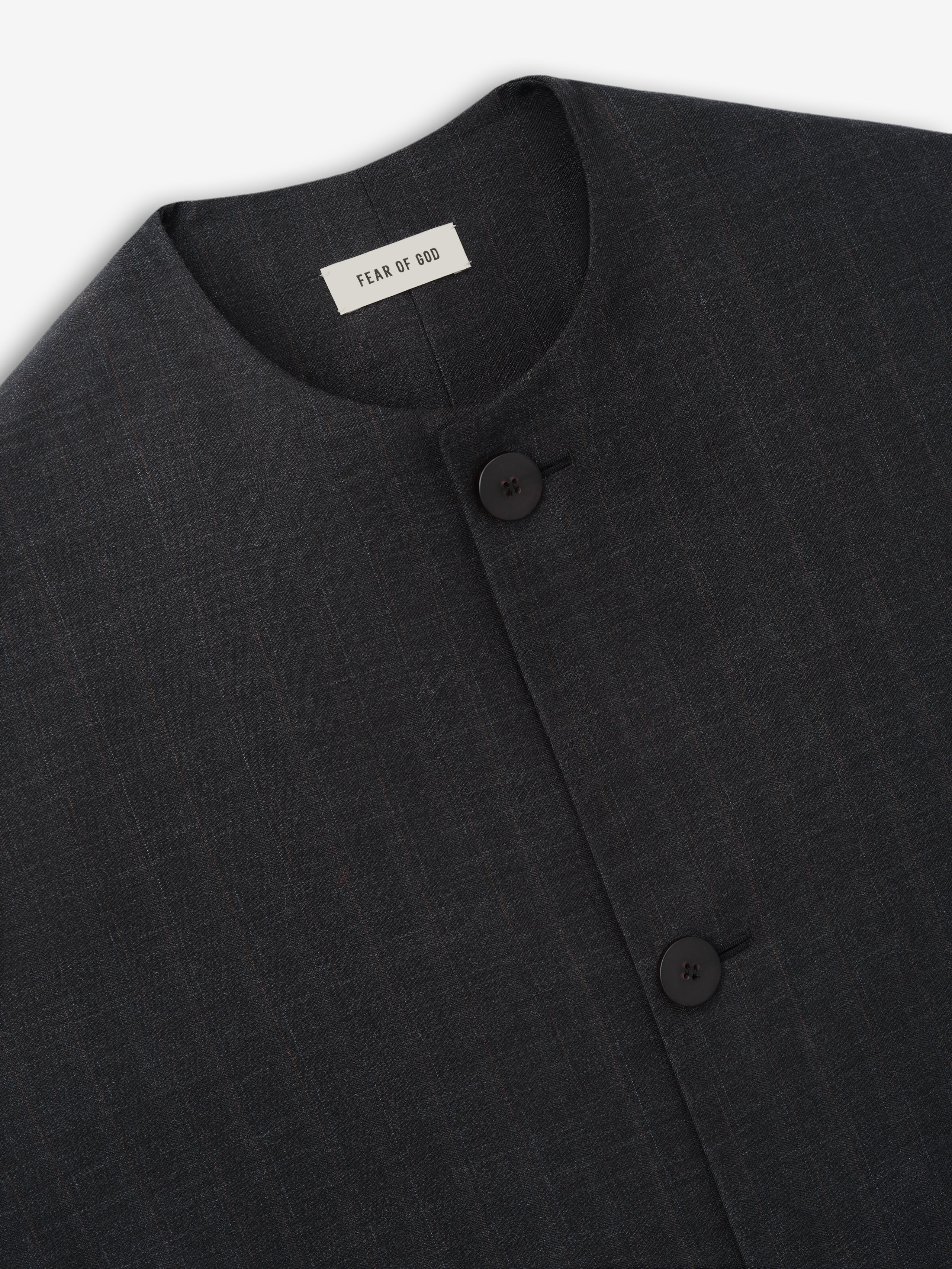 Close-up of dark charcoal textured fabric jacket with round neckline and two black buttons on front panel
