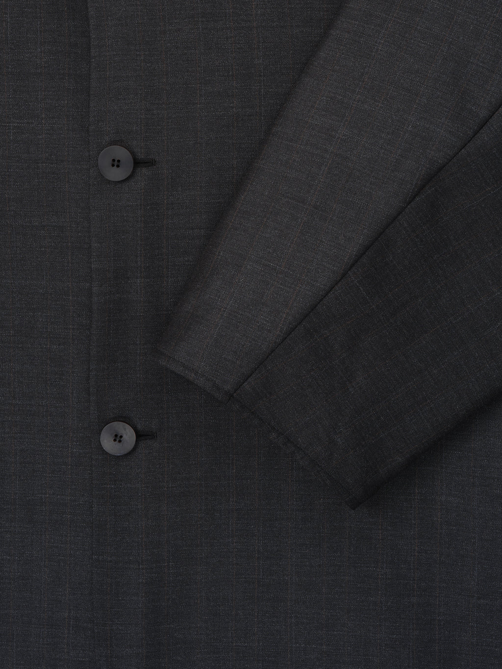 Close-up of dark gray jacket fabric with subtle check pattern and two black buttons on front panel