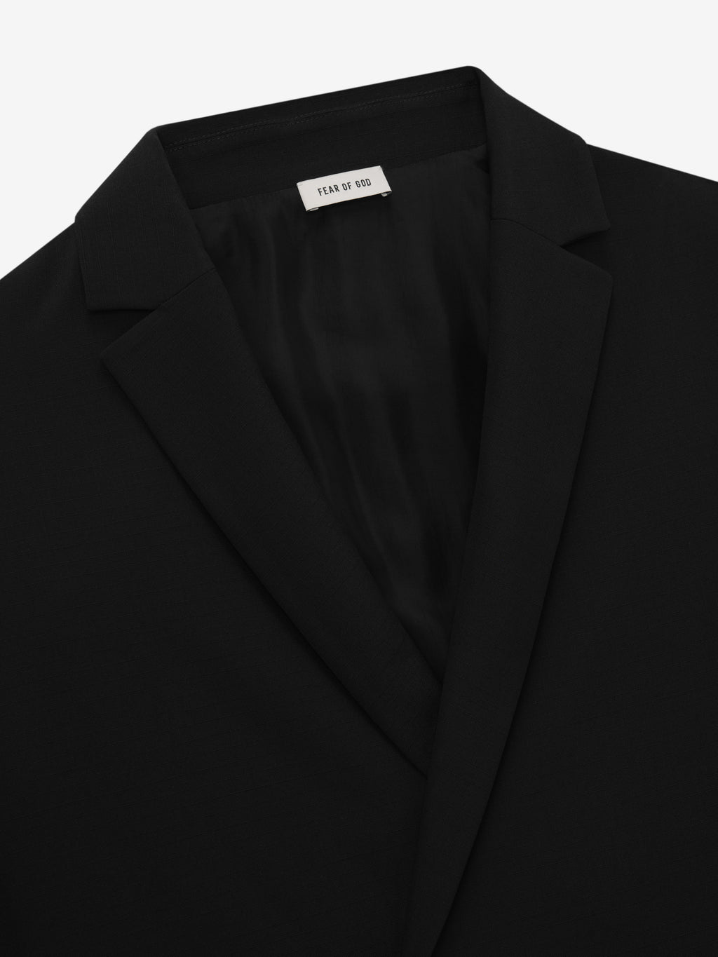 close-up view of black tailored long jacket lapels and silk-lined interior collar by Fear of God