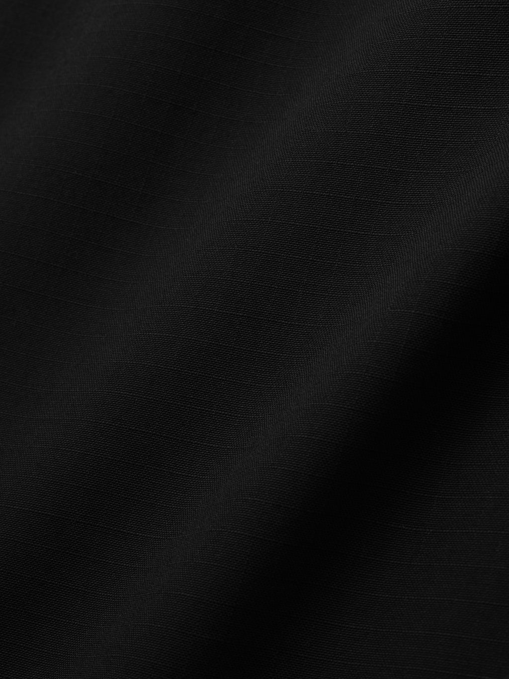 close-up of black compact rip-stop virgin wool fabric with subtle grid texture and smooth drape