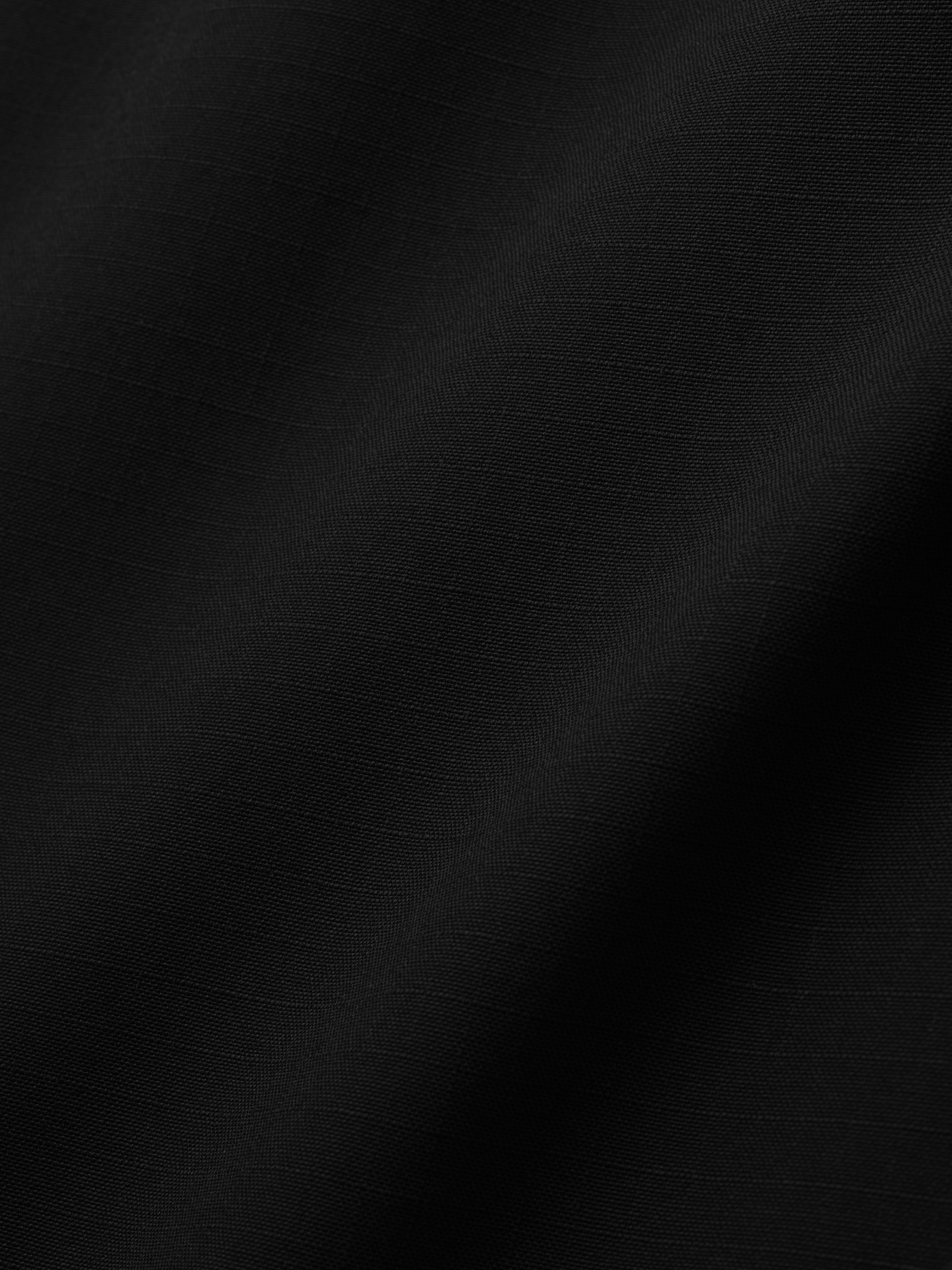 close-up of black compact rip-stop virgin wool fabric with subtle grid texture and smooth drape