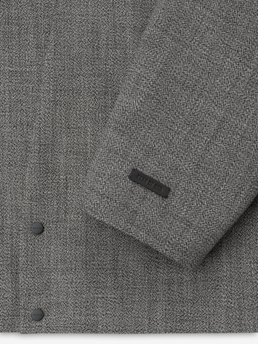detailed view of grey virgin wool mouliné fabric with matte snap buttons and embossed brand label on sleeve cuff