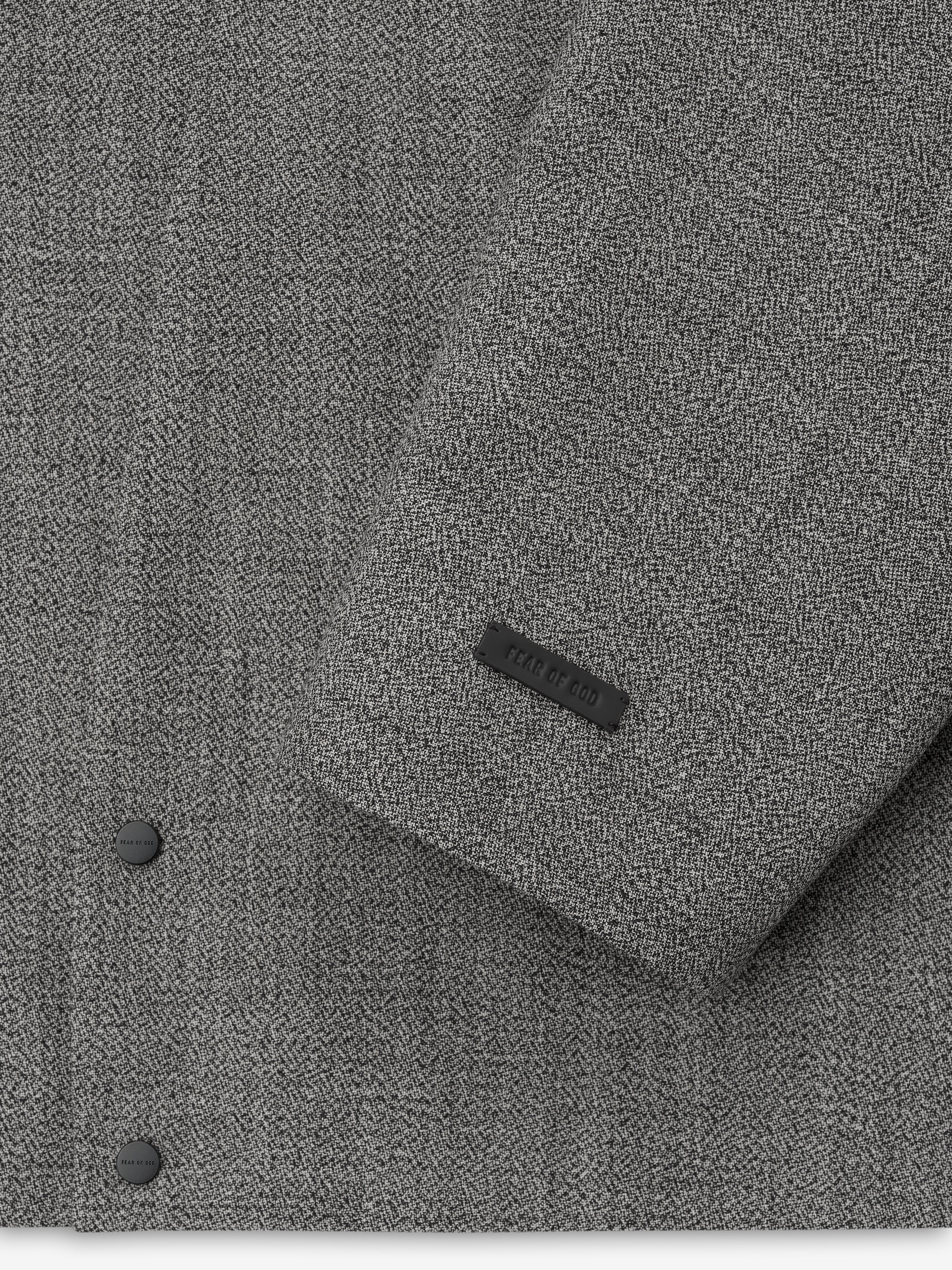 detailed view of grey virgin wool mouliné fabric with matte snap buttons and embossed brand label on sleeve cuff
