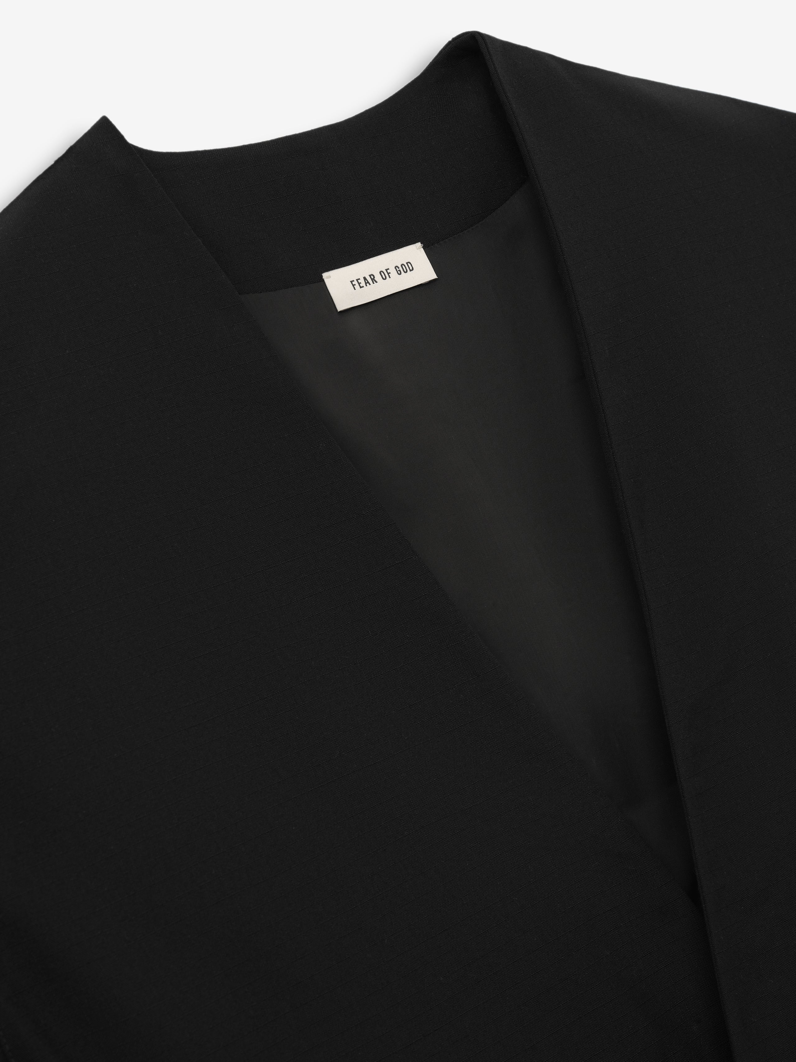 close-up of black collarless lightweight wool ripstop fabric and smooth Bemberg cupro lining inside cropped jacket