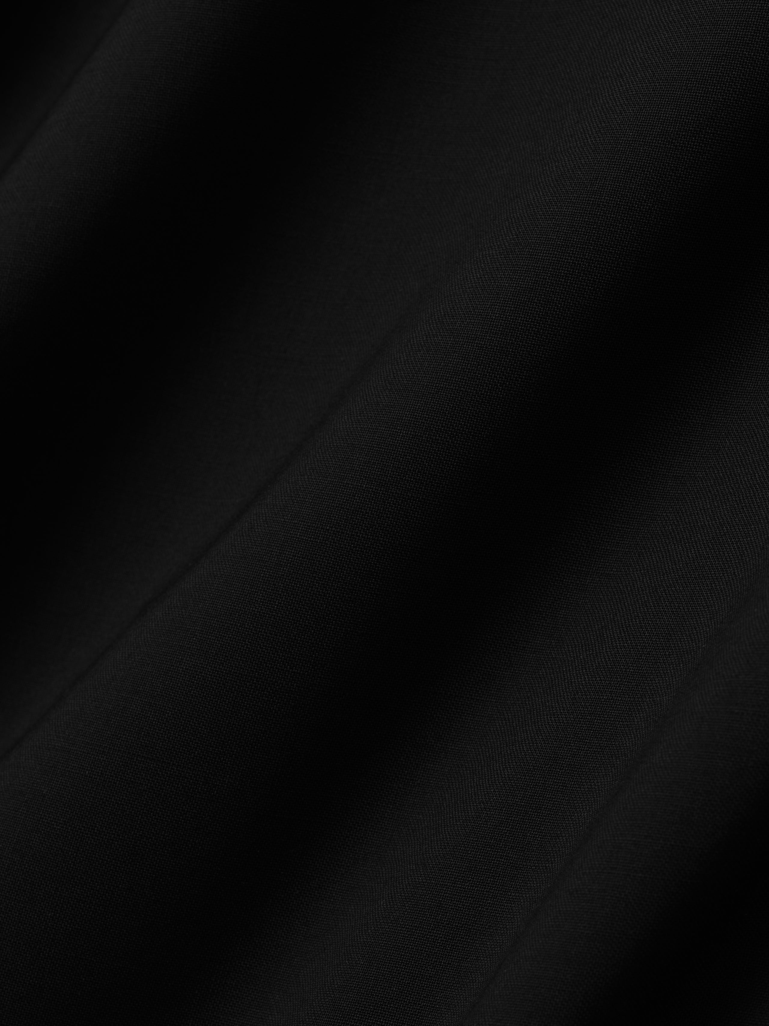 close-up of smooth lightweight black wool canvas fabric with subtle texture and soft drape