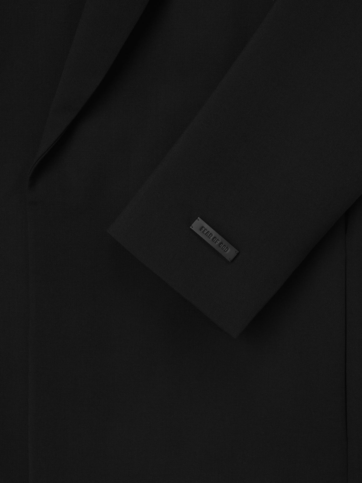 Double Weave Wool Belted Jacket close up in black showing the lapel sleeve cuff and Fear of God label as Outerwear