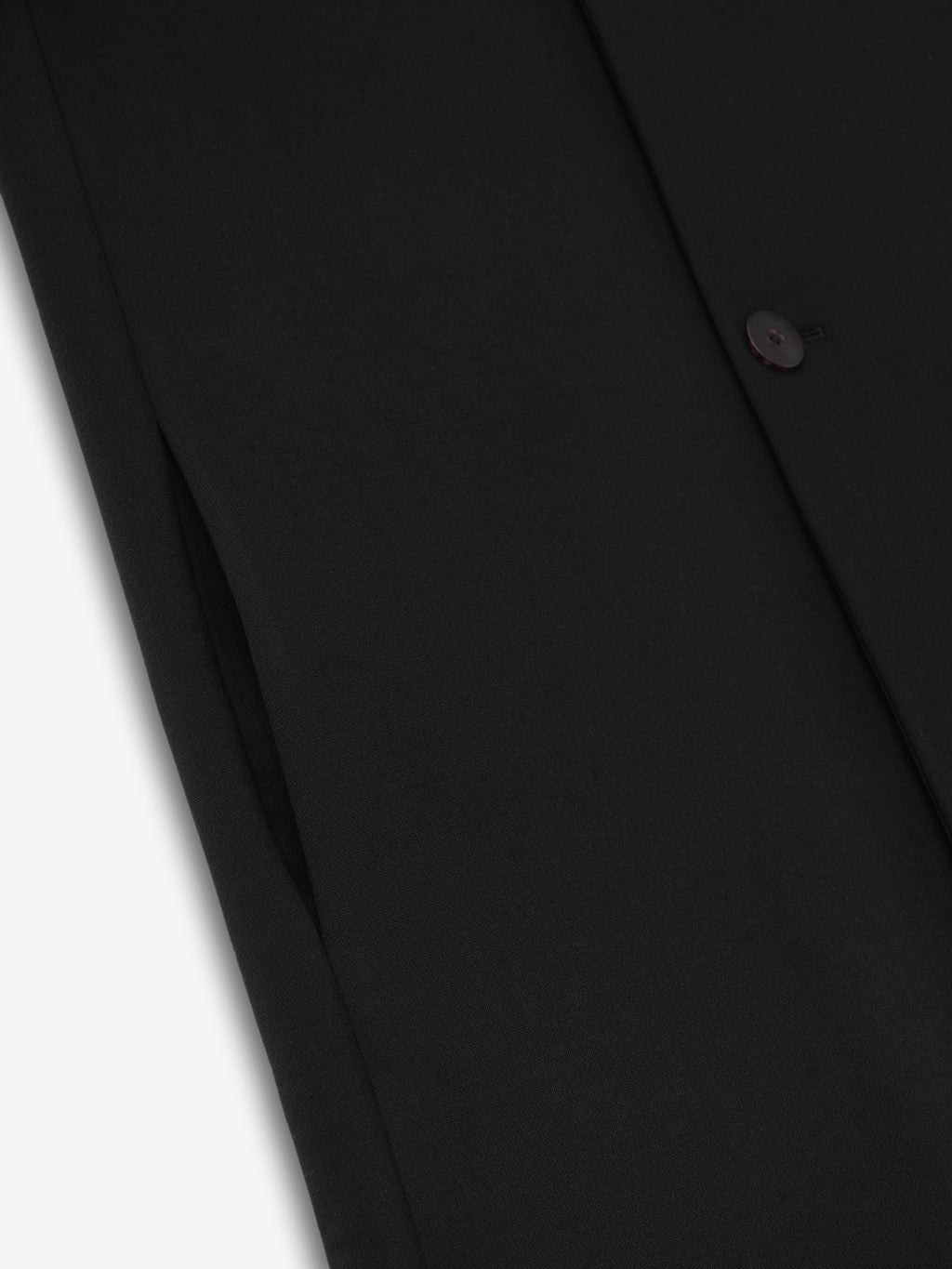 close-up detail of black double weave virgin wool fabric and button on lapelless double-breasted coat