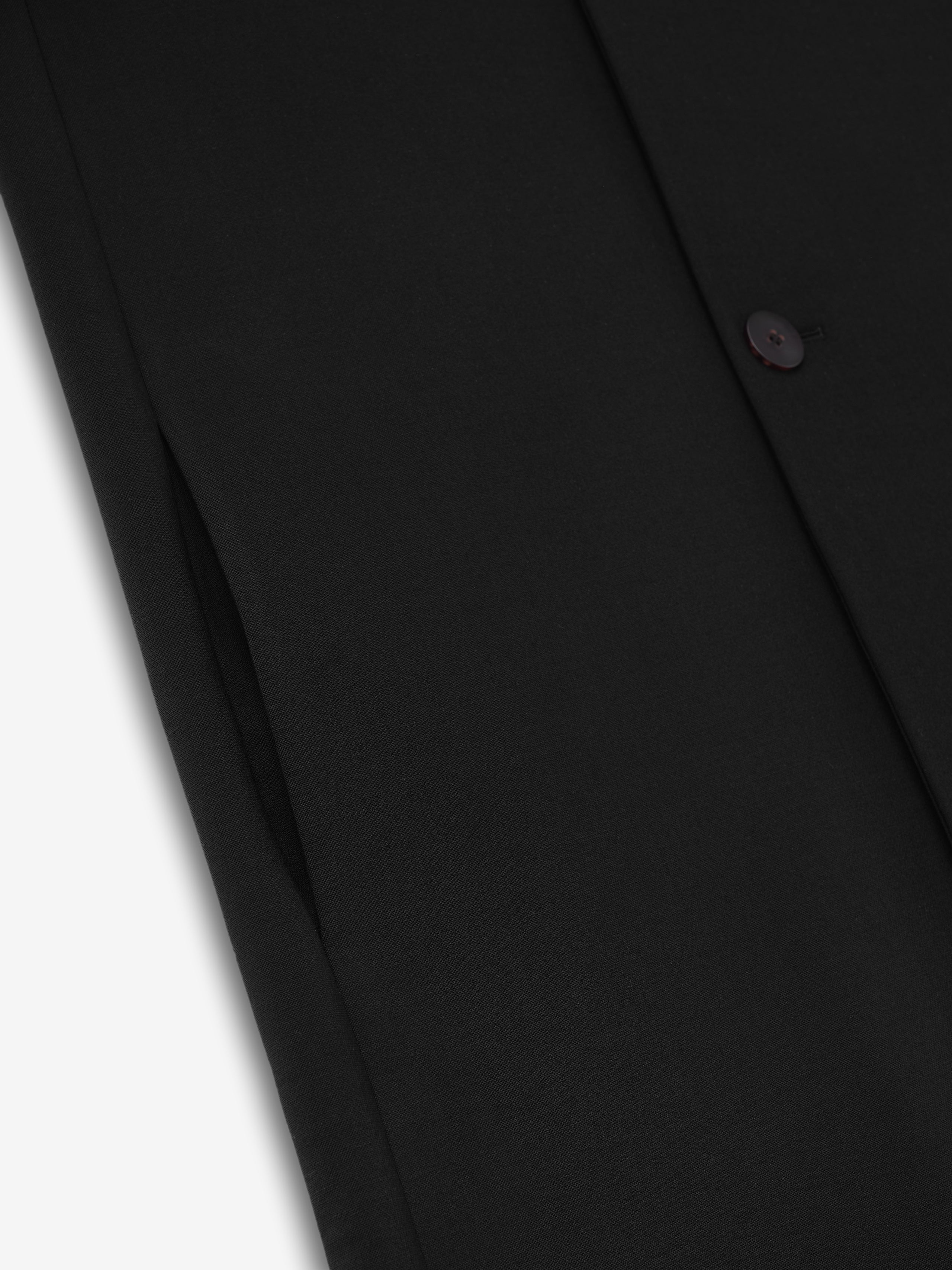 close-up detail of black double weave virgin wool fabric and button on lapelless double-breasted coat