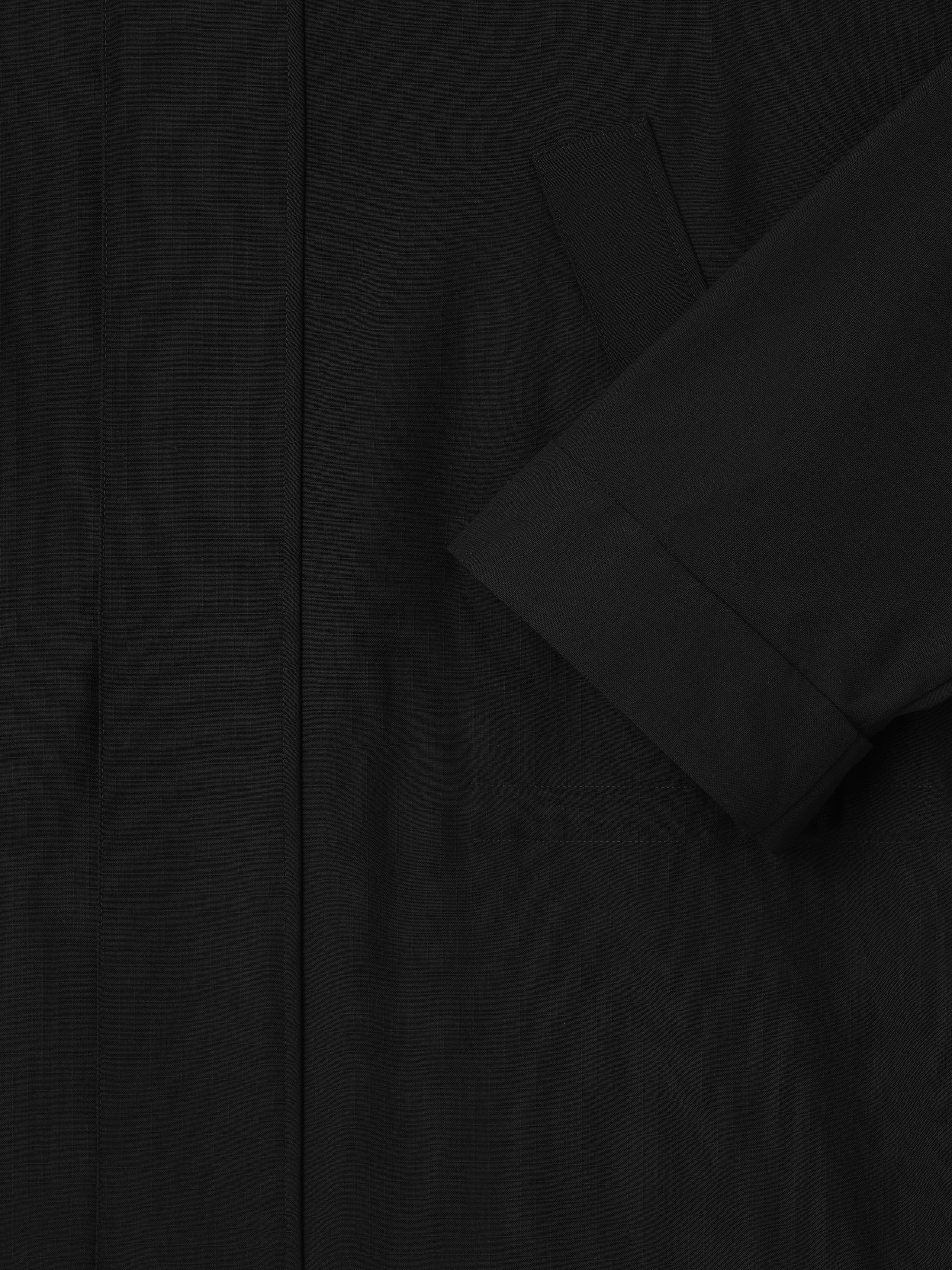 close-up of black lightweight rip-stop virgin wool parka sleeve and welted front pocket detail
