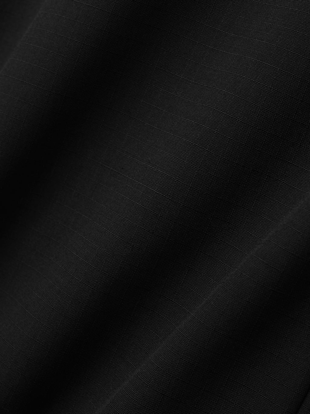 textured close-up of black lightweight rip-stop virgin wool fabric with subtle grid pattern and soft folds