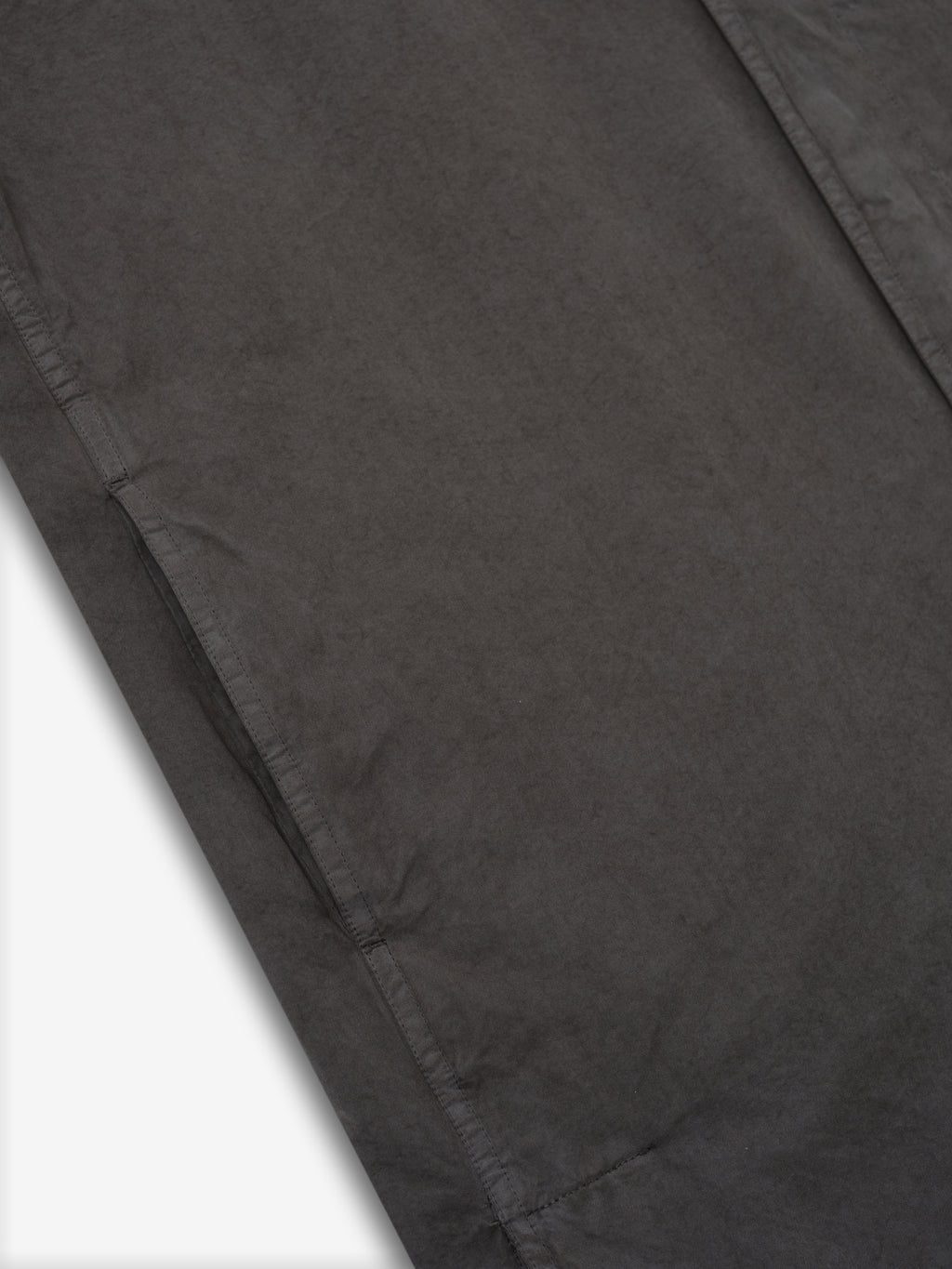 Close-up of dark gray car coat fabric with visible side seam stitching on white background