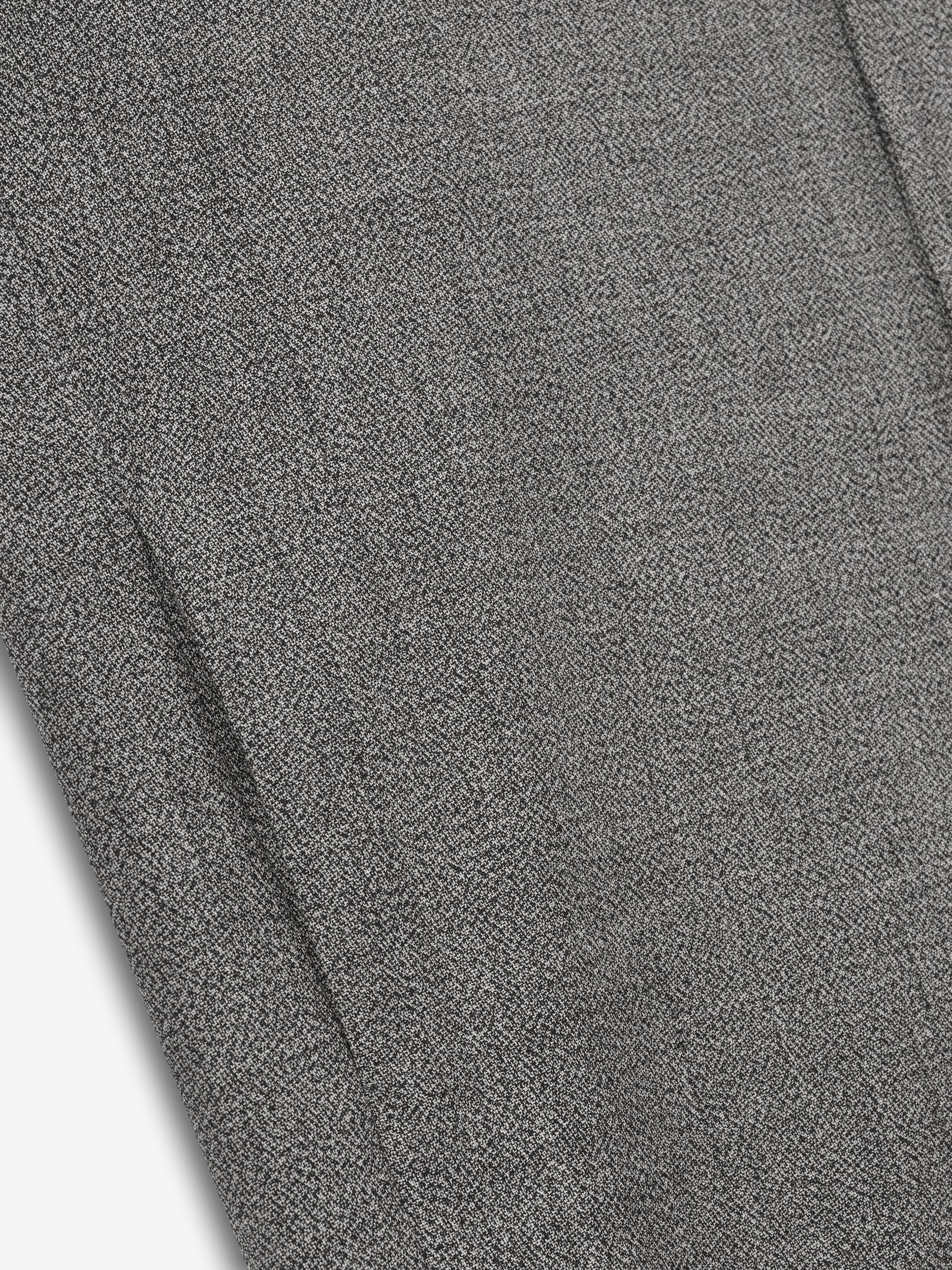 detailed close-up of gray mouline virgin wool fabric showing subtle textured weave of relaxed trench coat