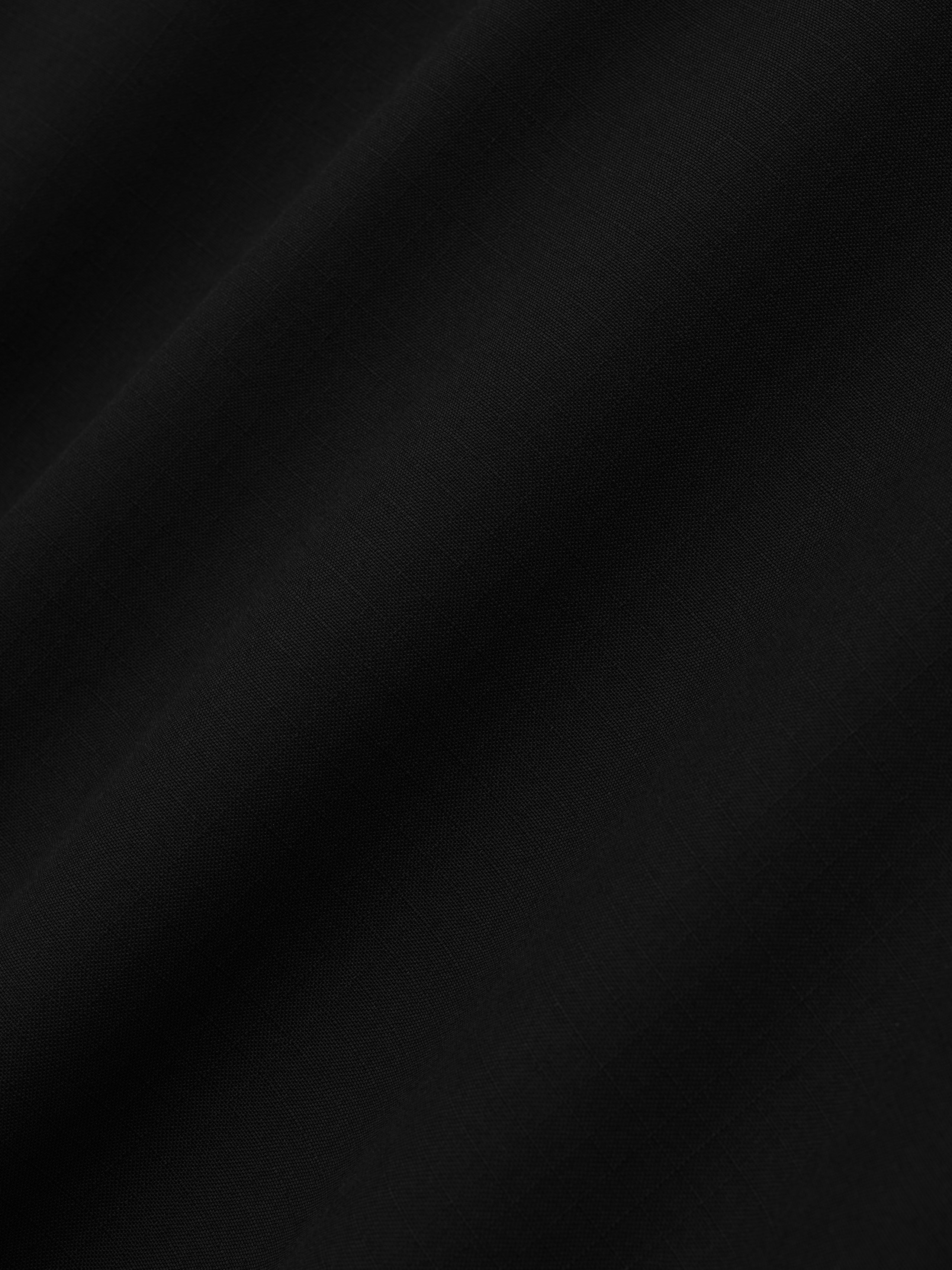 close-up of black lightweight ripstop virgin wool fabric with subtle grid texture and smooth finish