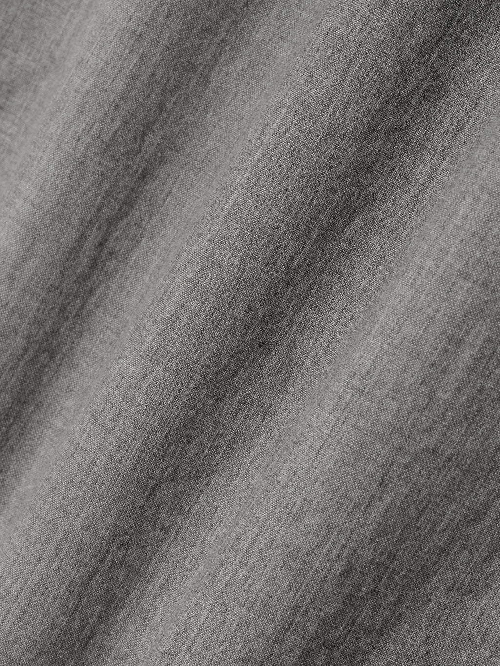 Close-up of textured medium gray fabric with subtle woven pattern and soft folds visible across surface