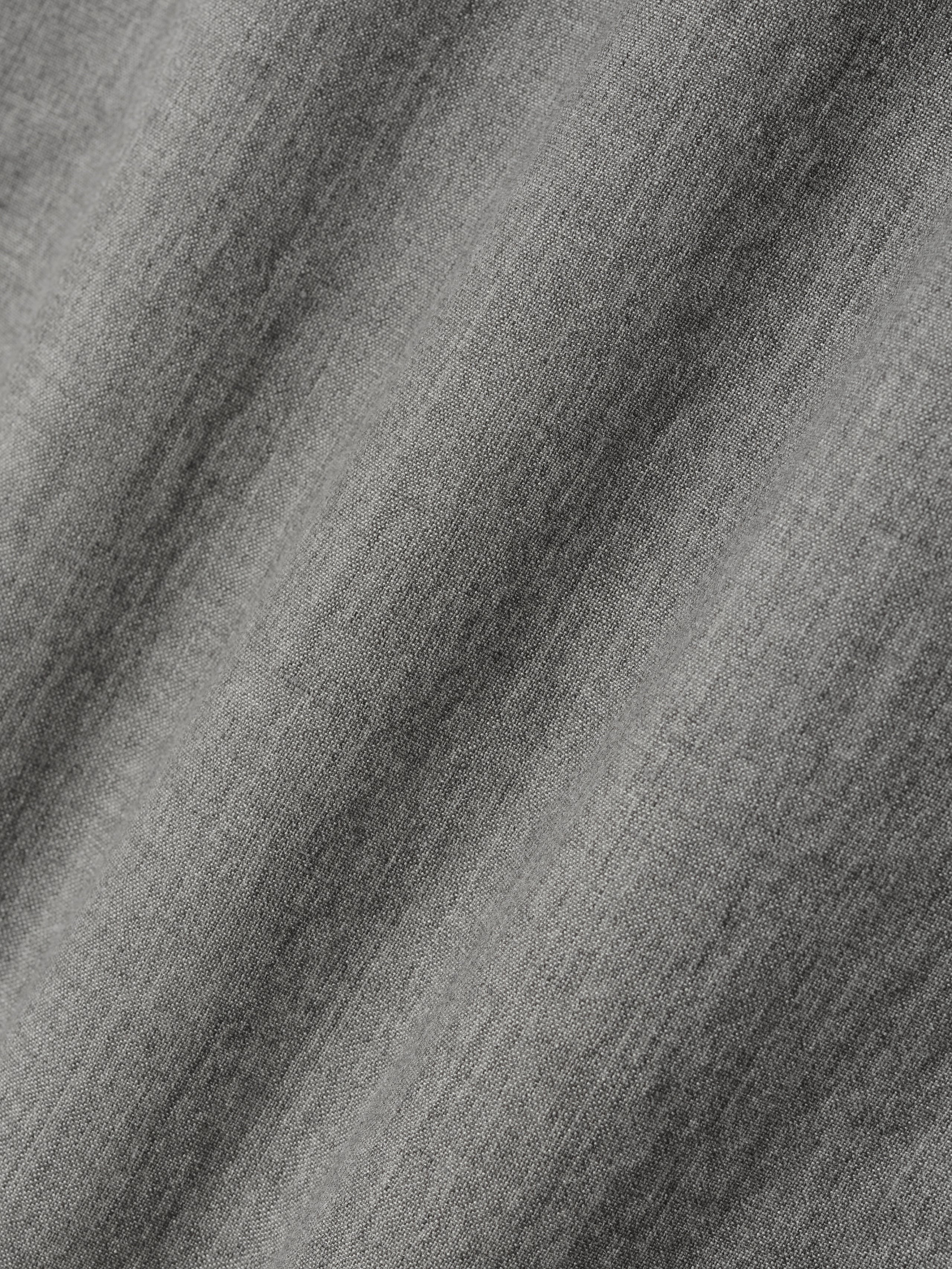 Close-up of textured medium gray fabric with subtle woven pattern and soft folds visible across surface