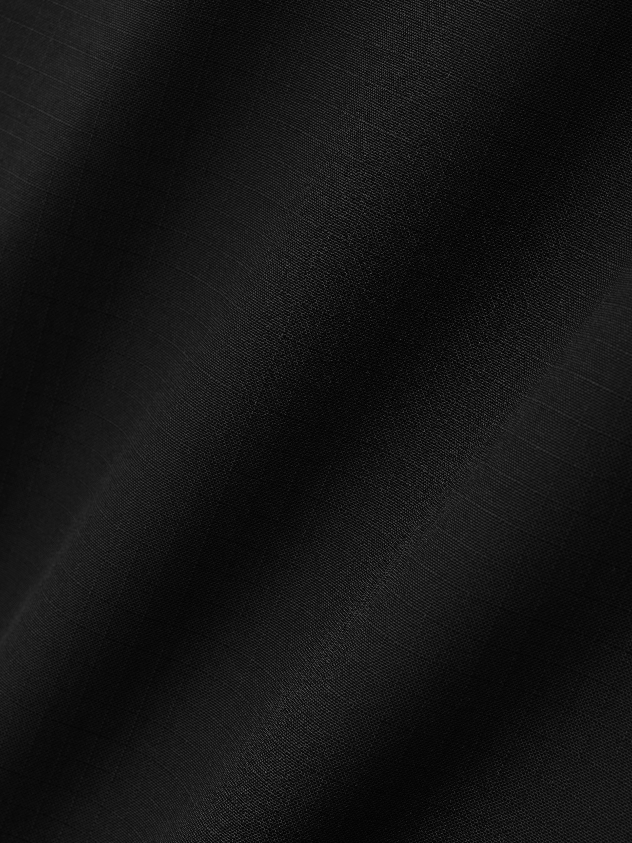 close-up of black ripstop virgin wool fabric with subtle grid texture and soft lightweight drape