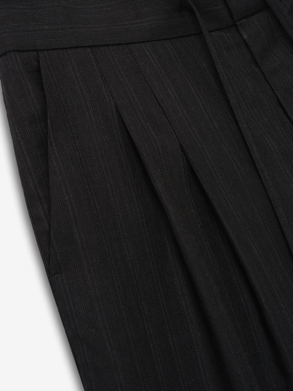 close-up of black super-fine yarn-dyed wool fabric with subtle vertical stripes and pleated detailing on baggy shorts