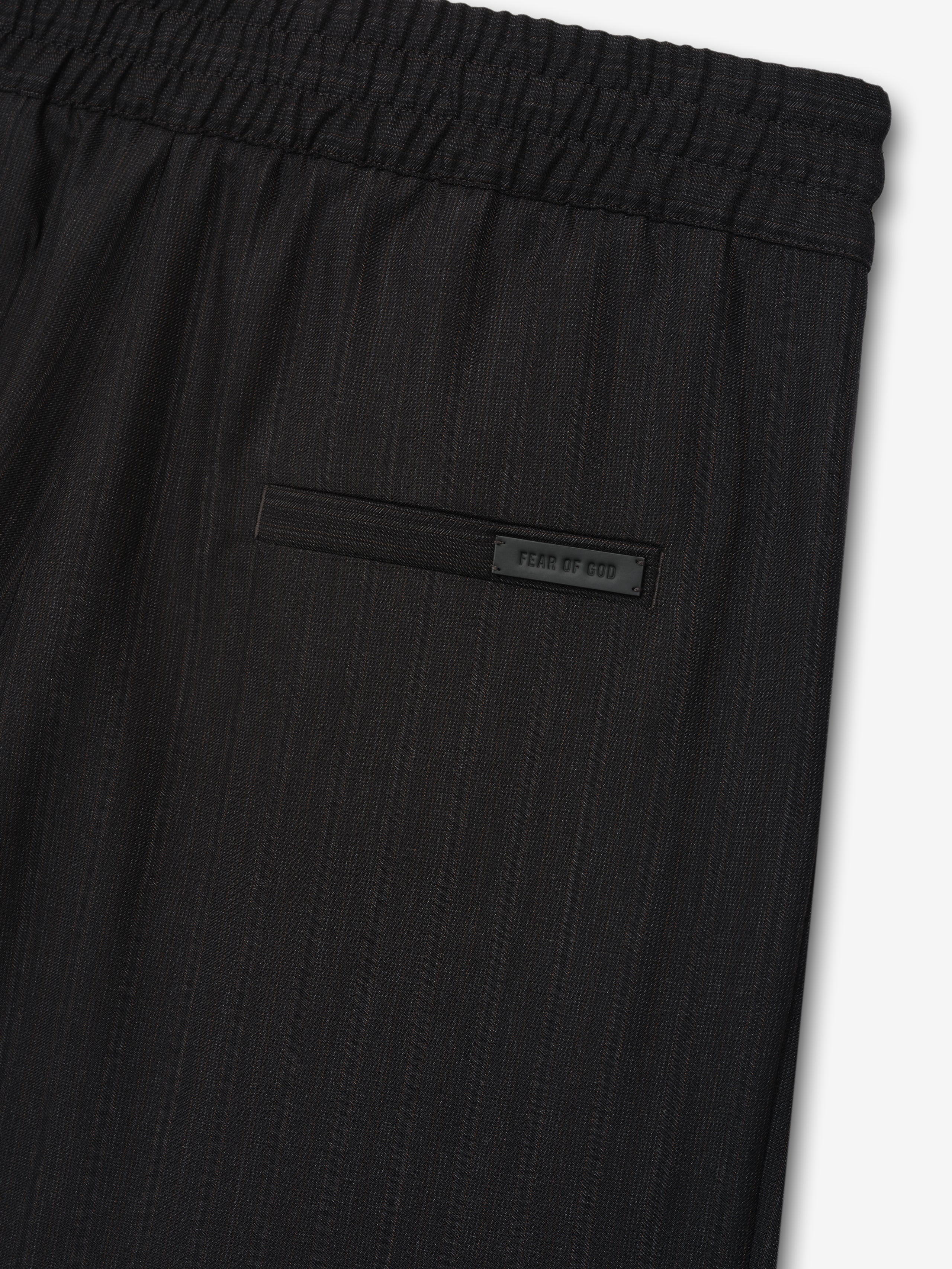 close-up of black striped wool fabric with elastic waistband and rear welt pocket featuring Fear of God label