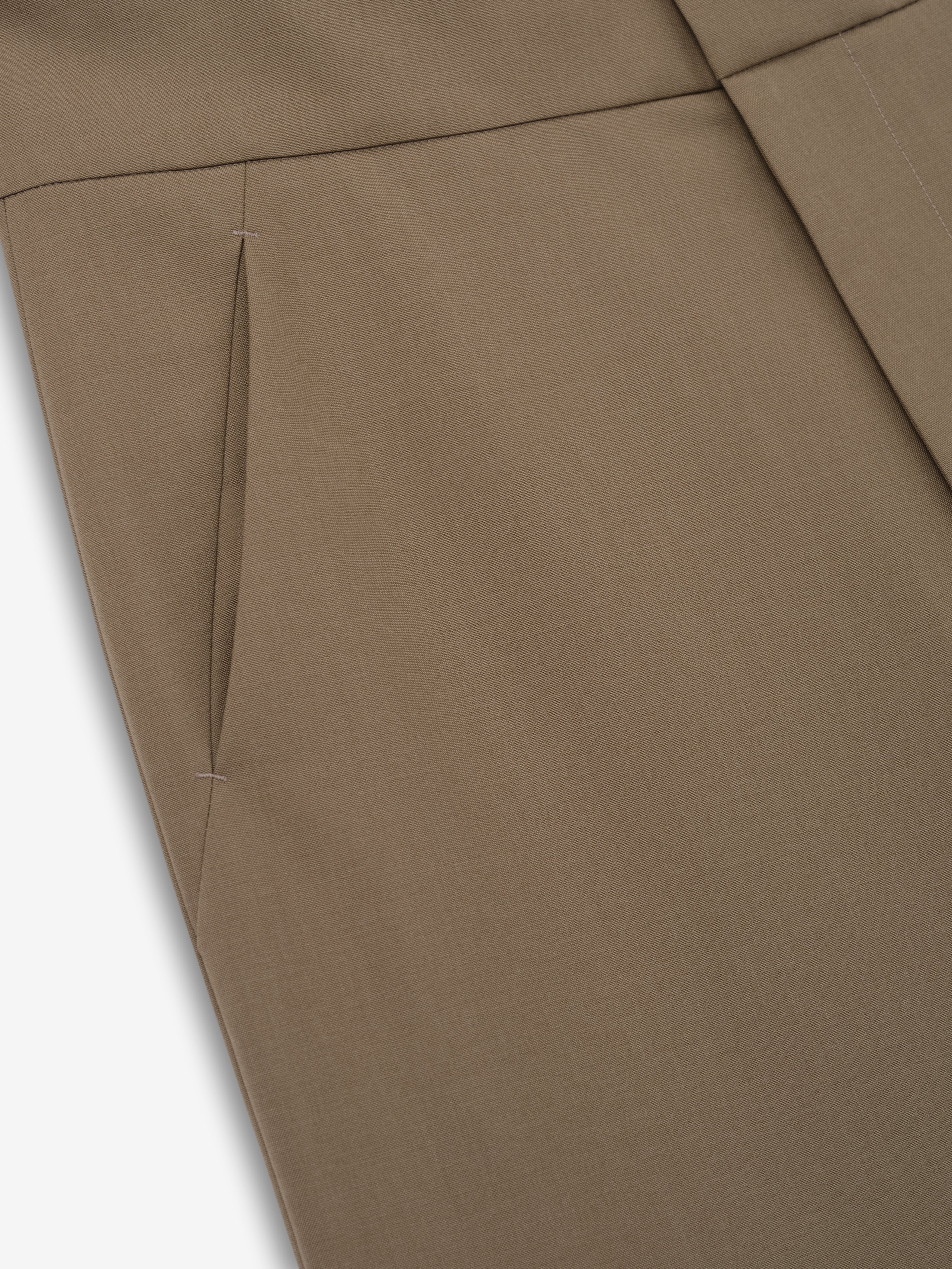 Close-up of clay-colored pants pocket with clean stitching and smooth fabric texture on a flat surface