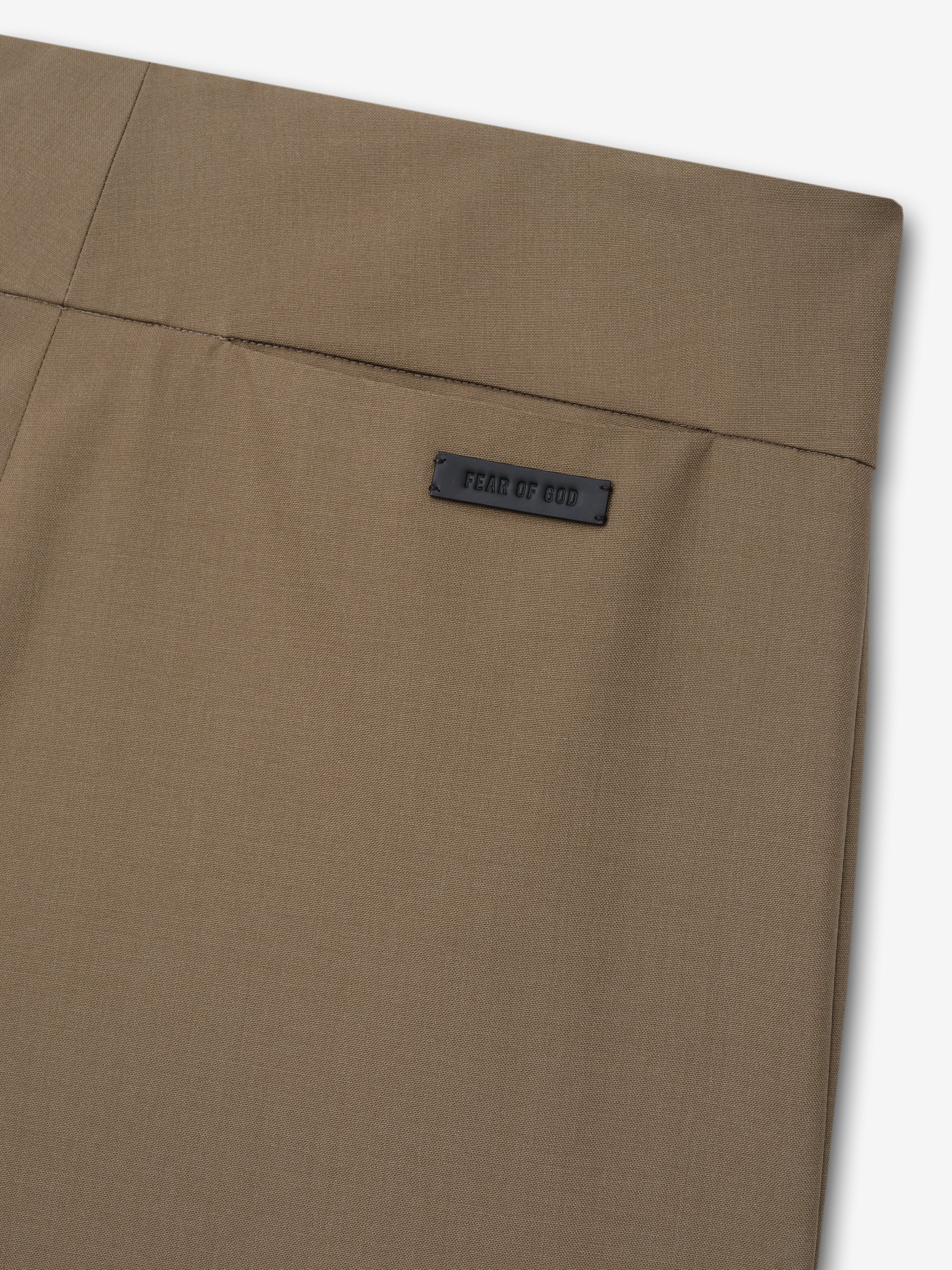 Close-up of smooth clay-colored fabric with a black rectangular label stitched near the upper edge