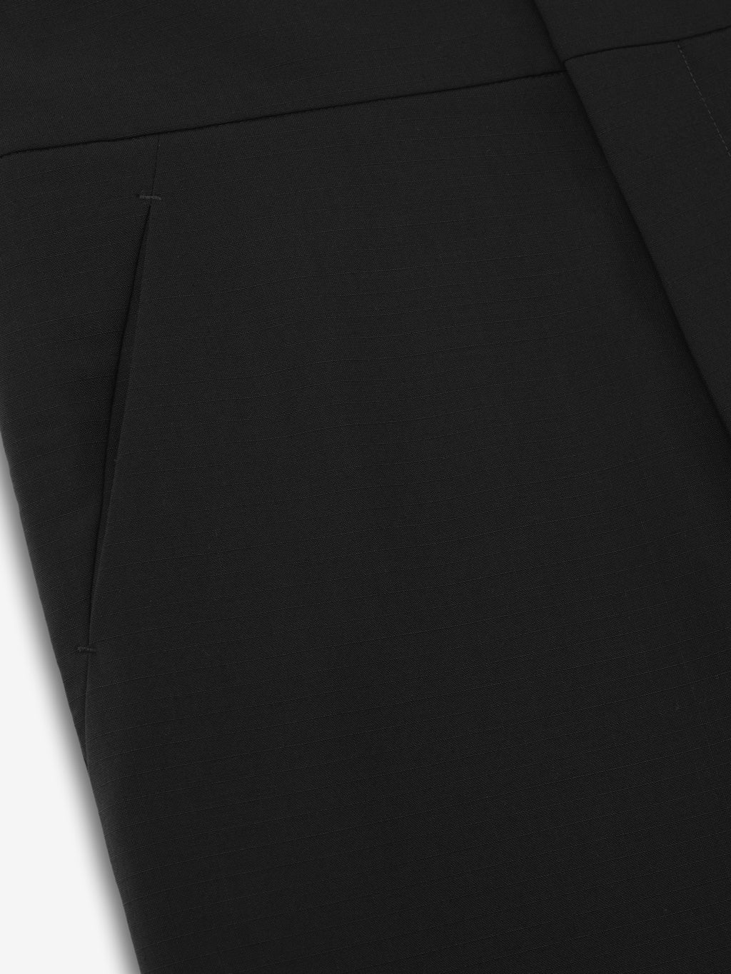 close-up of black ripstop virgin wool casual pants showing side seam pocket and flat front construction on smooth fabric